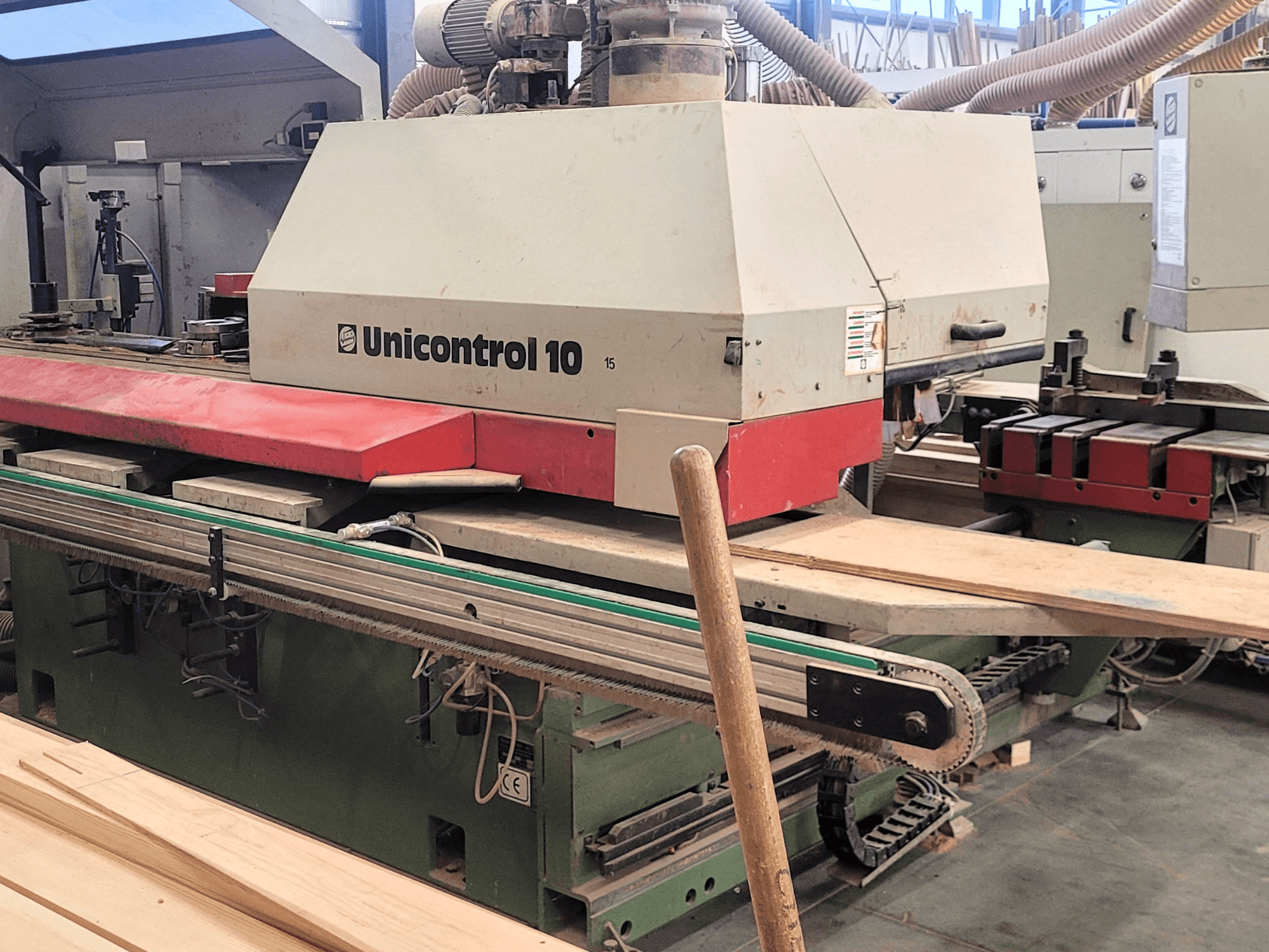 Centro de processamento CNC Unicontrol 10 da WEINIG/DIMTER, vista frontal com placas de madeira e equipamento numa oficina.