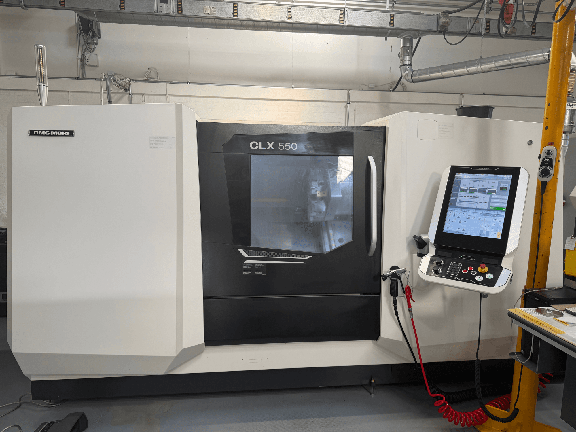 Torno horizontal DMG MORI CLX 550 V4, vista frontal com painel de controlo e ecrã, apresentando funcionalidades avançadas de maquinagem.