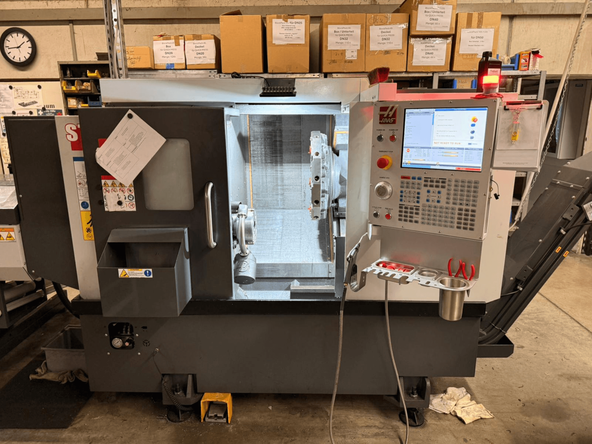 O torneiro horizontal HAAS ST-15, visto de lado, apresenta um painel de controlo digital e componentes operacionais.
