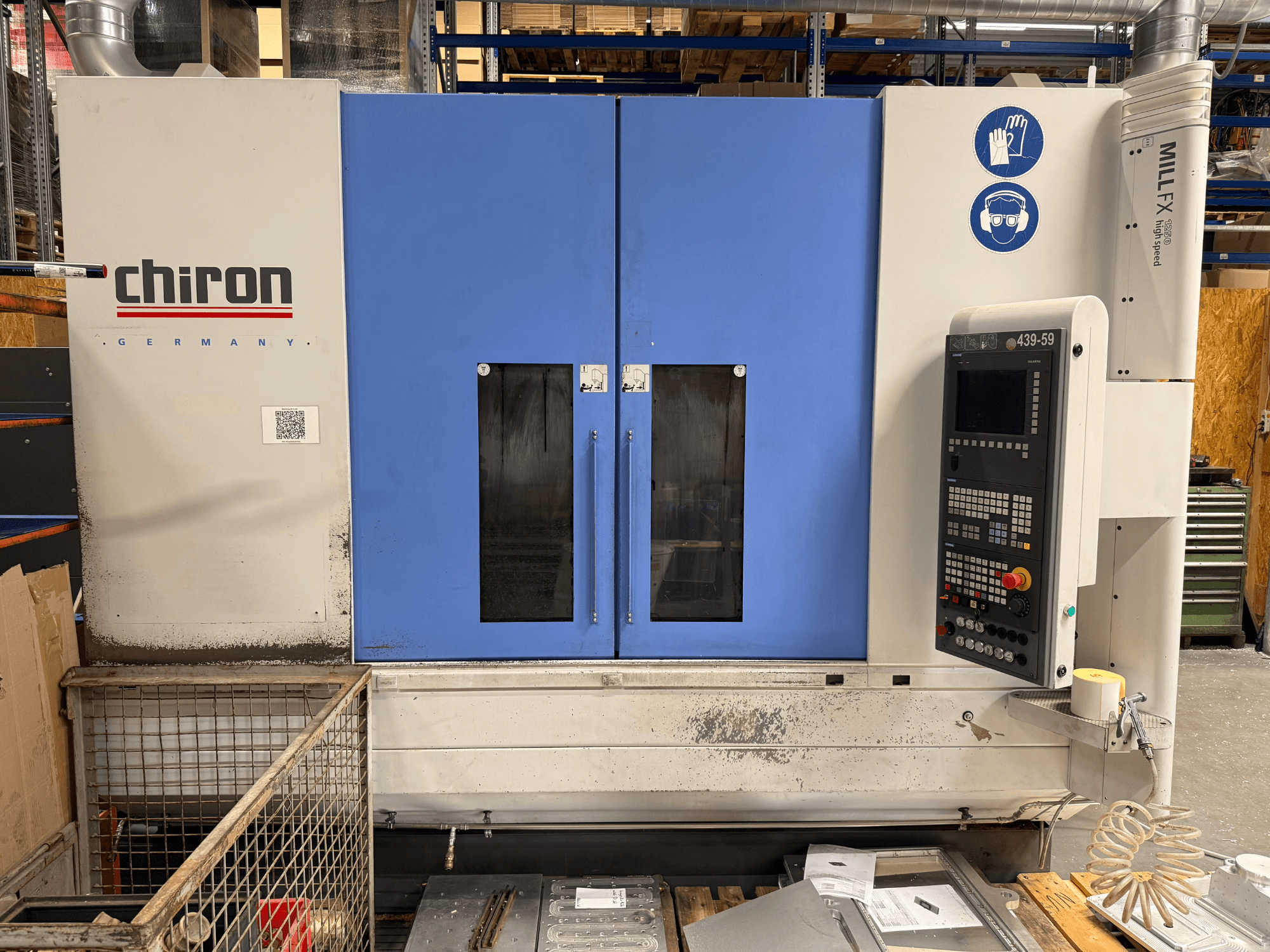 Centro de usinagem vertical CHIRON MILL FX 1250, vista frontal, com painel de controlo e símbolos de segurança, pronto para trabalhos de precisão.