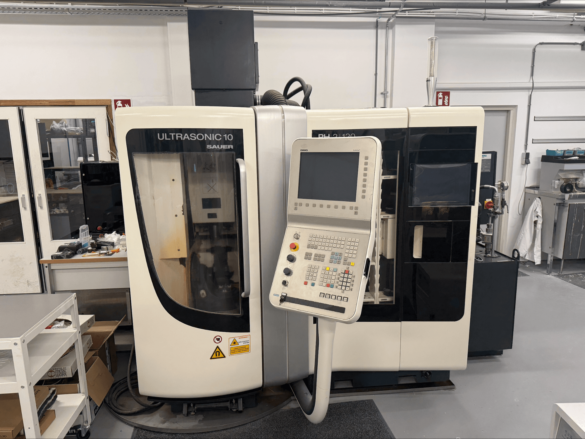 Centro de maquinação vertical DMG Sauer Ultrasonic 10 + PH 2 | 120, vista frontal, com painel de controlo e grande janela de visualização.
