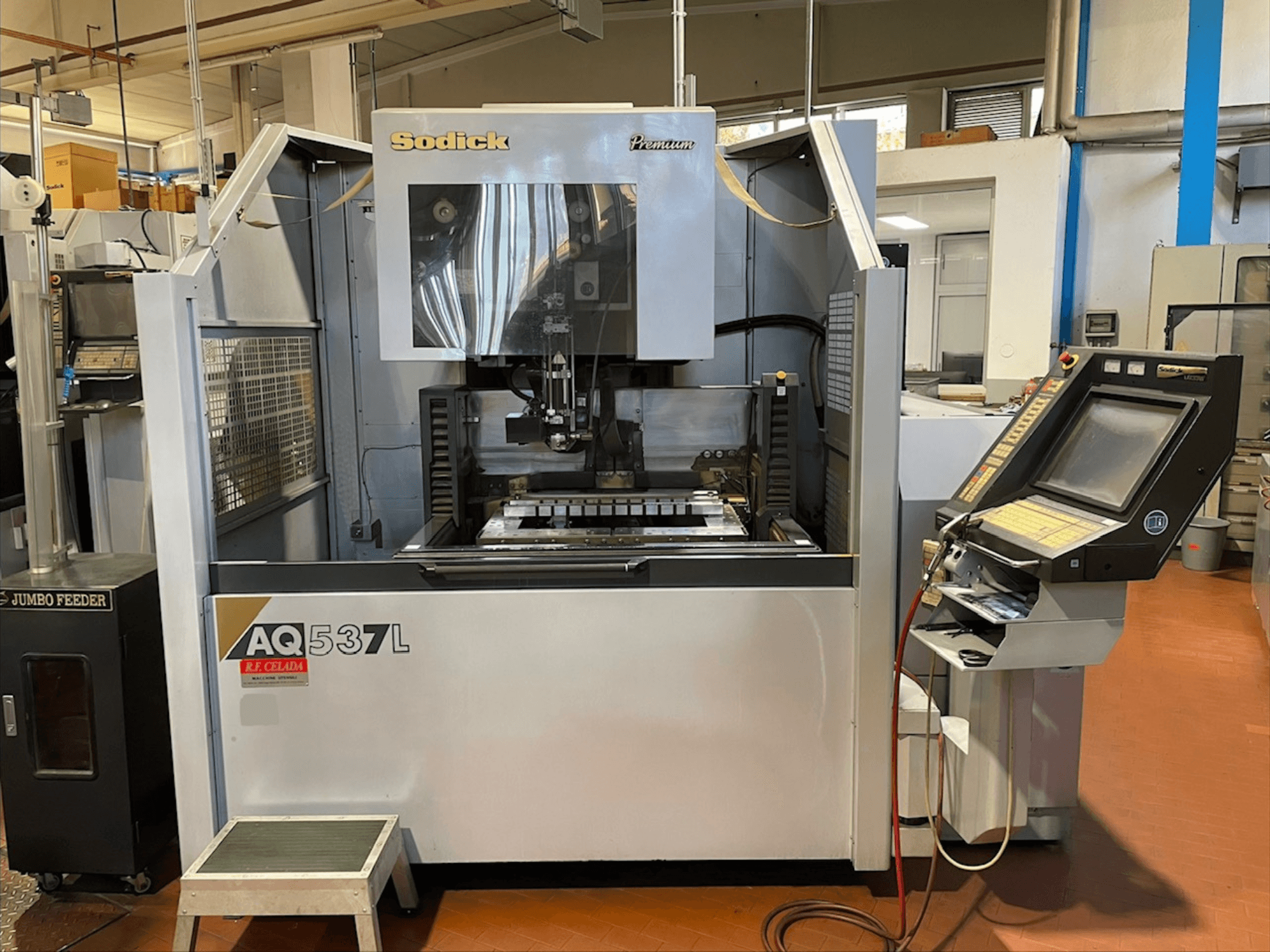 Máquina EDM de fio Sodick AQ537L em vista frontal, mostrando o painel de controlo e a área de maquinação com componentes visíveis.