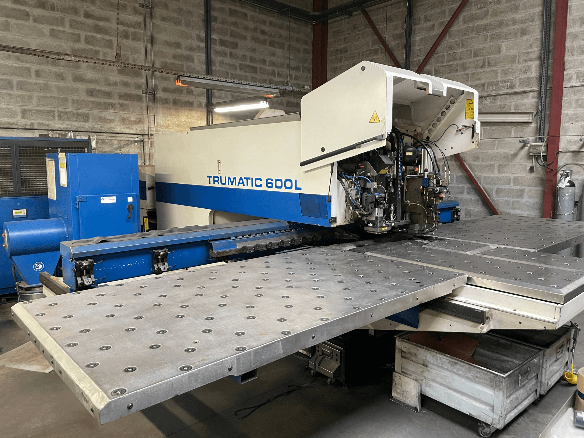Máquina de corte a laser CO2 TRUMPF TRUMATIC TC 600L, vista frontal com mesa de corte de metal e painel de controlo visíveis.