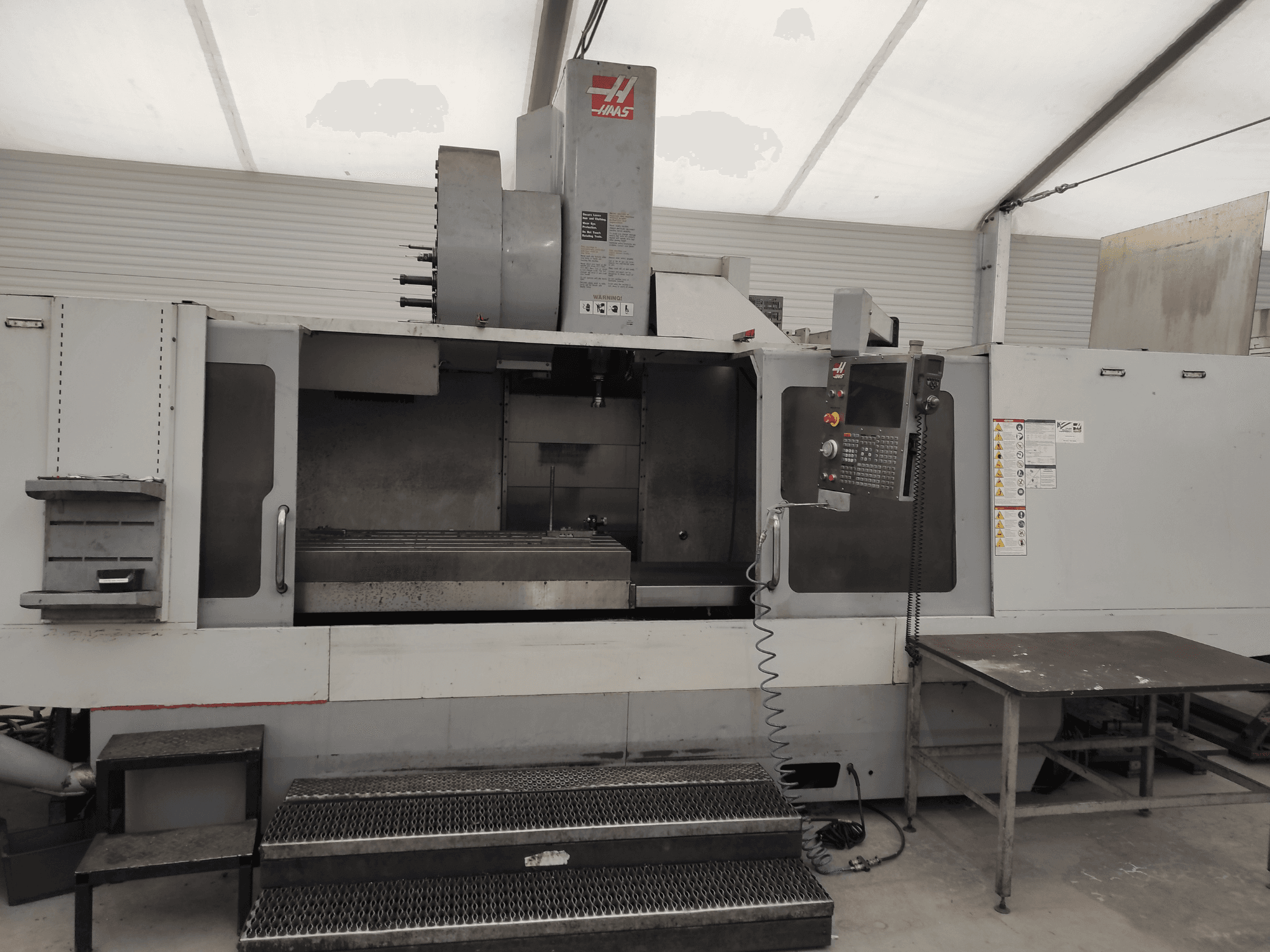 Centro de maquinação vertical HAAS VF-10/50HE, vista frontal mostrando o painel de controlo, a base da máquina e o degrau acessível para operação.