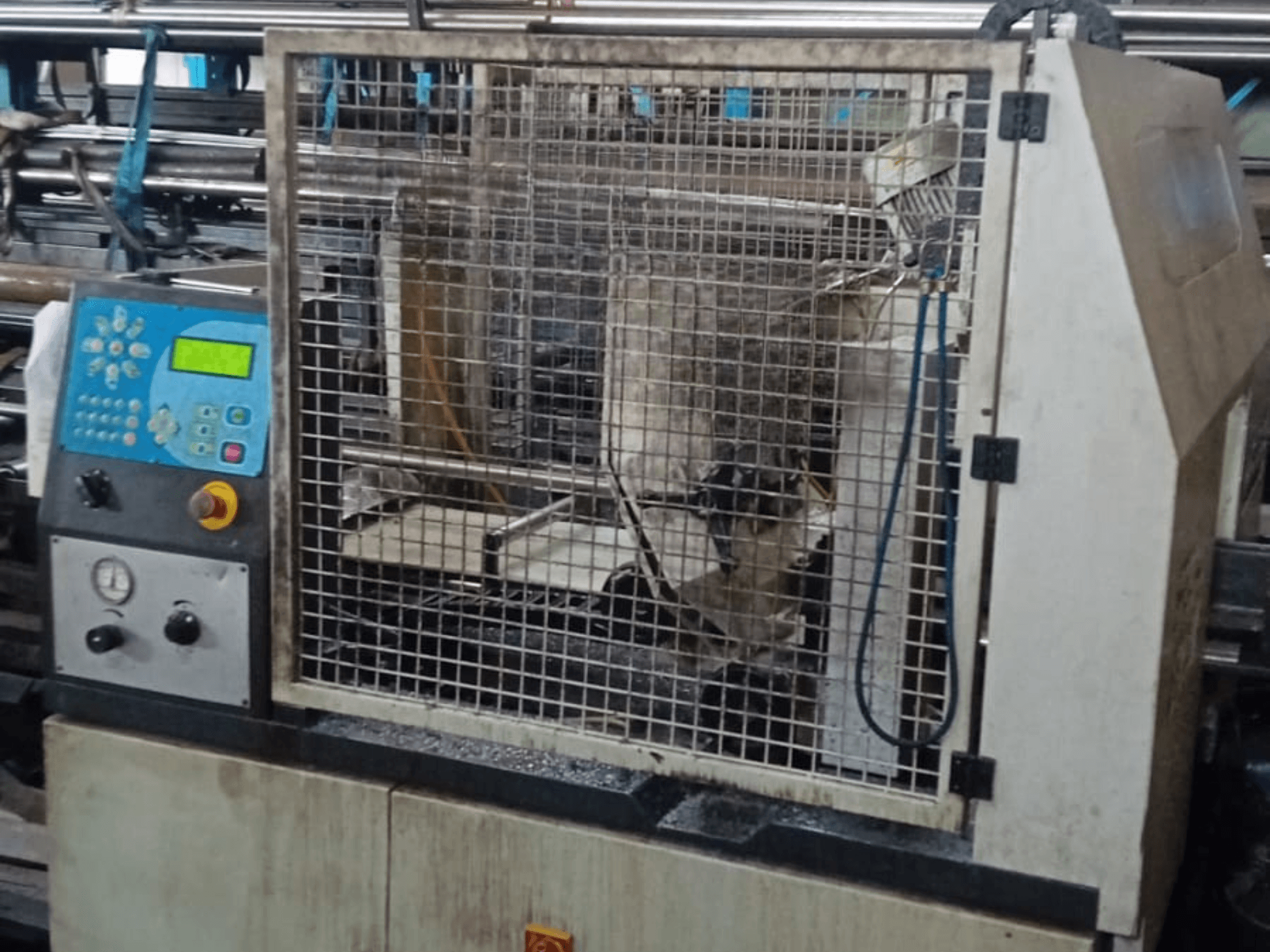 Serra de fita para metal Macc 381 AV, vista frontal, mostrando o painel de controlo, a gaiola de segurança e os restos de metal na base.