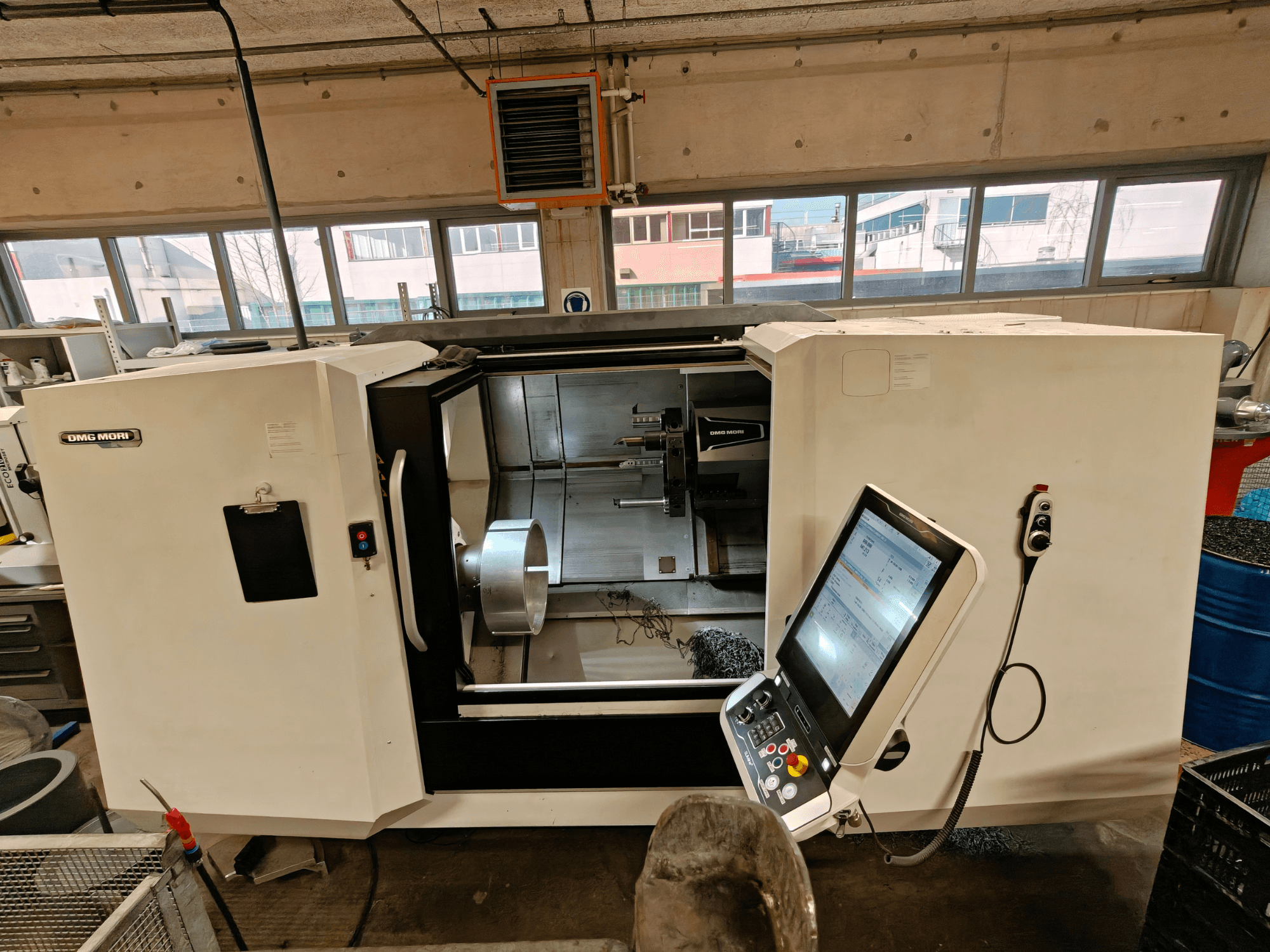 Vista frontal de um torneiro horizontal DMG MORI CLX 550, mostrando o painel de controlo e a área de trabalho aberta.