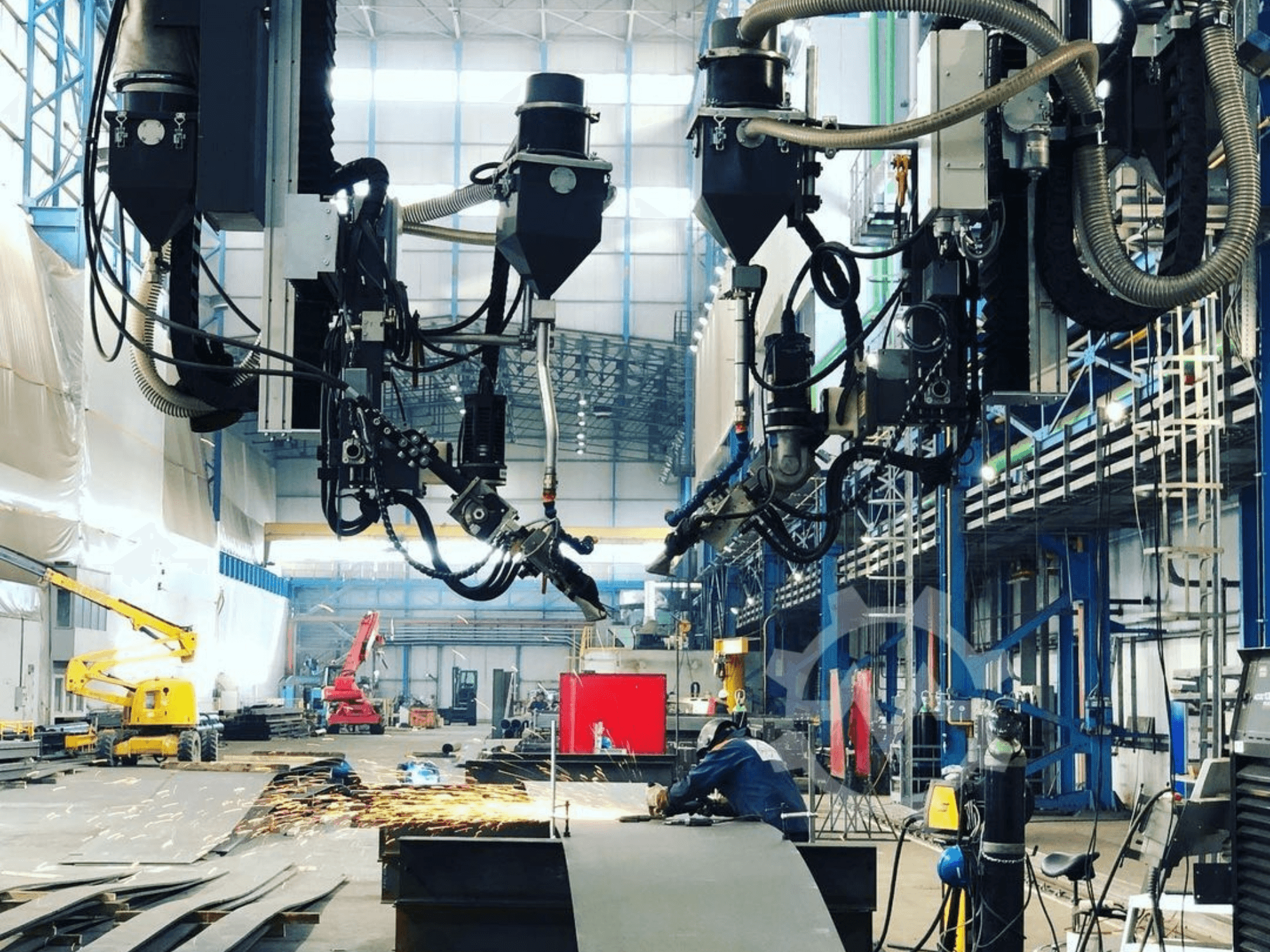 Máquina de corte robótica num ambiente industrial, com faíscas a voar, vista de lado; possui vários acessórios e mangueiras.