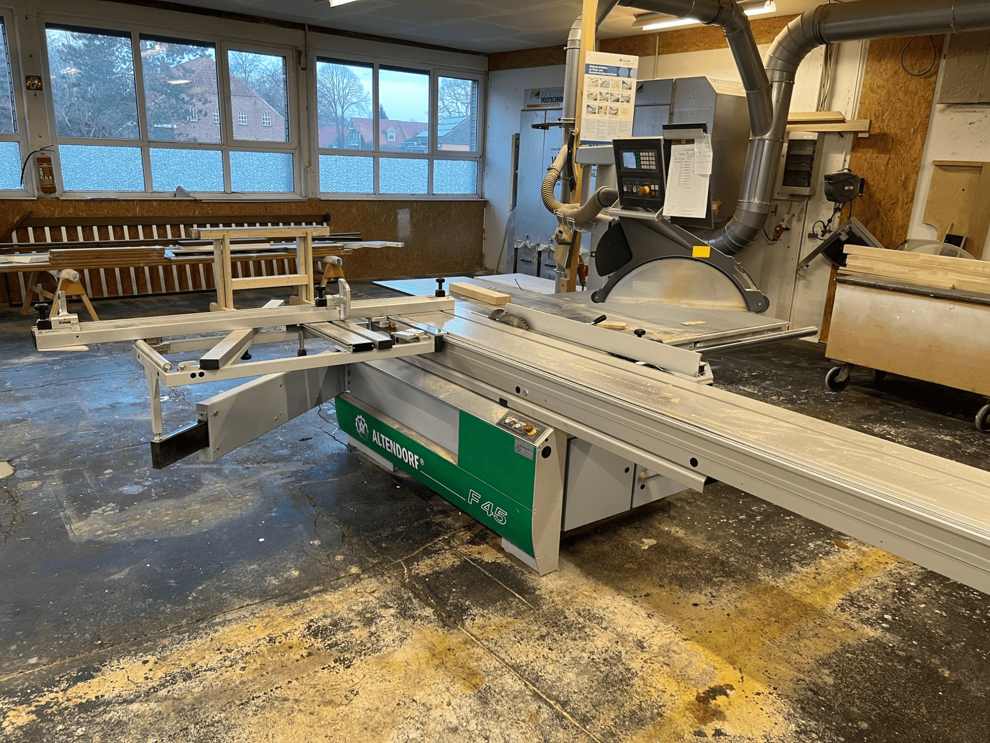 Serra de mesa Altendorf F45 numa oficina, vista frontal mostrando o braço ajustável e o painel de controlo, ideal para tarefas de corte de precisão.