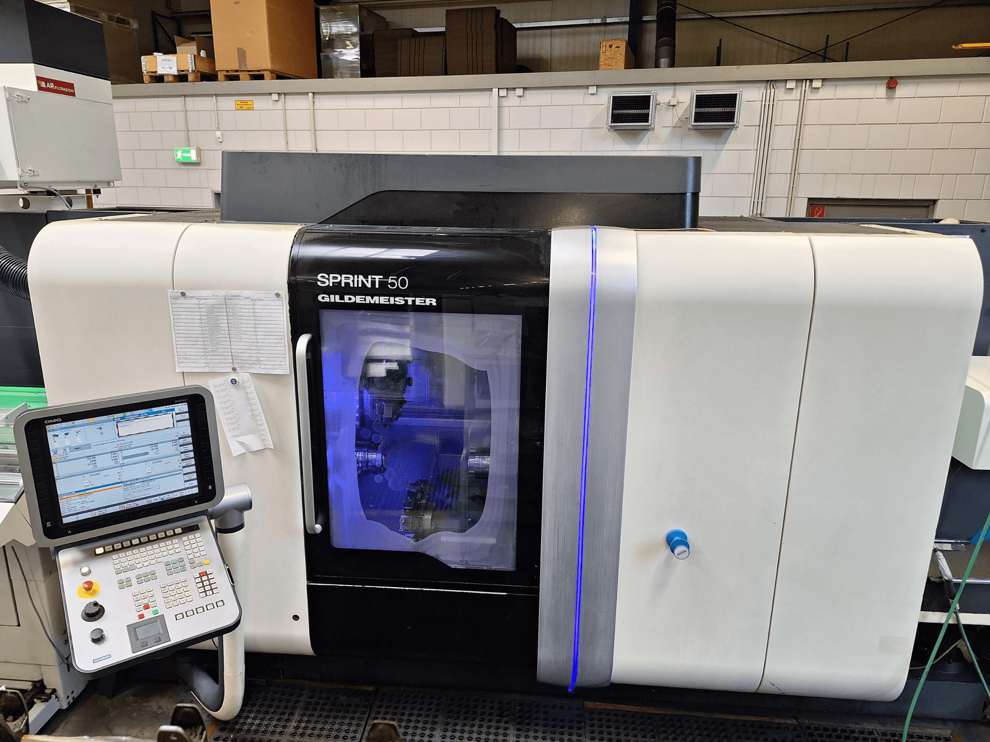 Máquina de tornear horizontal DMG Sprint 50 2T, vista frontal, com painel de controlo e caixa transparente que mostra a maquinaria no interior.