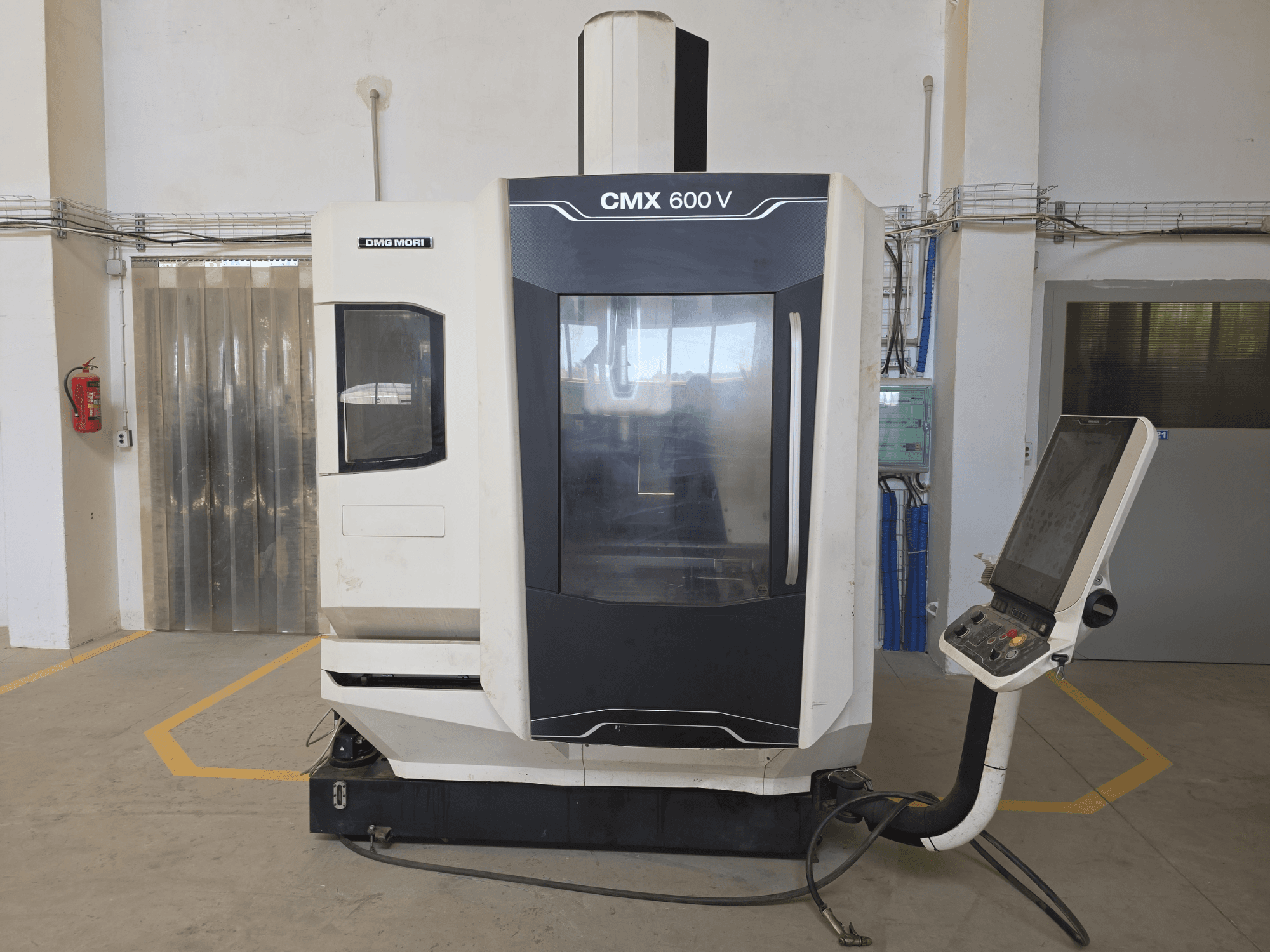 Centro de maquinação vertical DMG MORI CMX 600 V, vista frontal, mostrando o painel de controlo e a grande janela transparente.