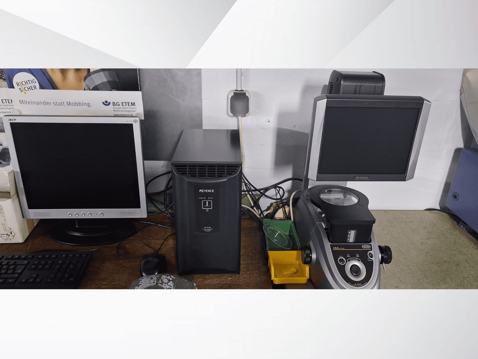 Dois monitores de computador, um Acer e um Keyence, ao lado de um dispositivo preto e de um microscópio, vistos de frente.