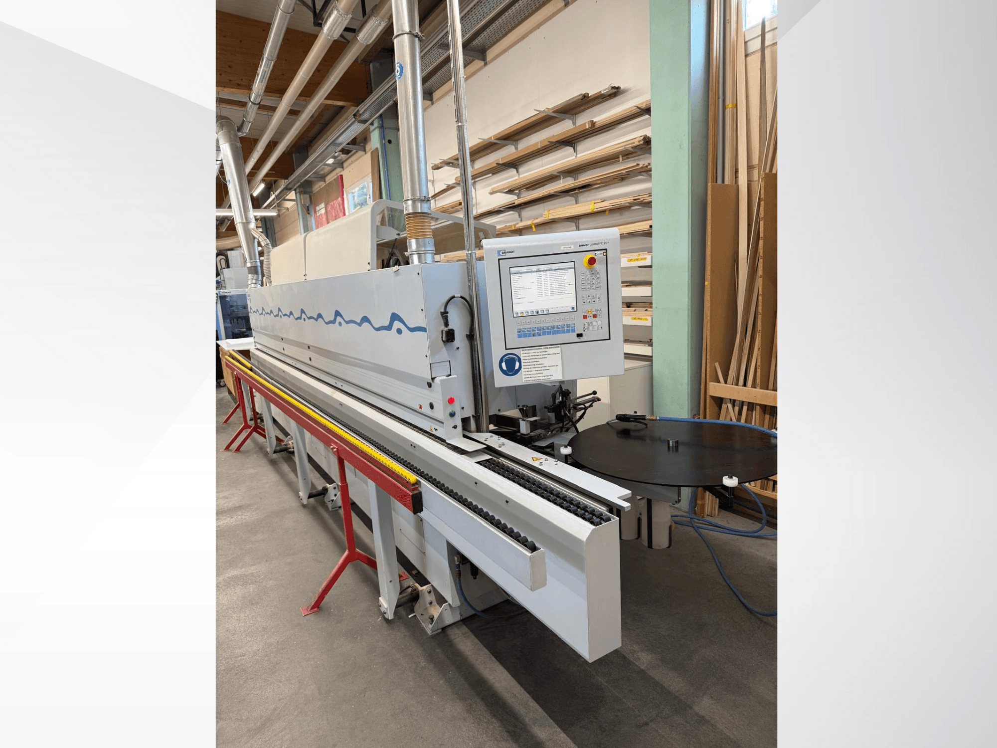 Vista frontal de uma coladeira de bordos automática HolzHer com painel de controlo, sistema de transporte e mesa de apoio redonda.