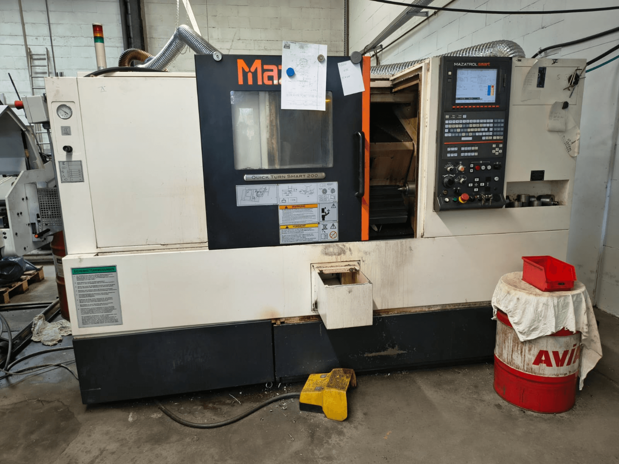 Mazak Quick Turn Smart 200, máquina de torneamento horizontal, vista frontal com painel de controlo, depósito de líquido de arrefecimento e marcações visíveis.