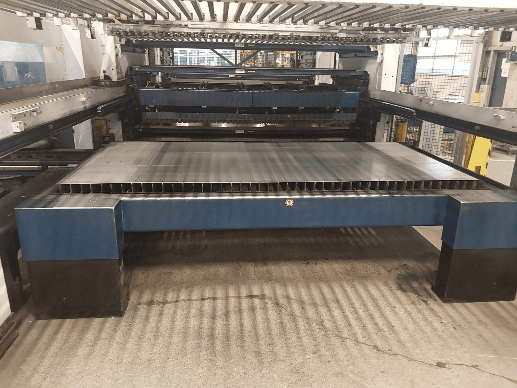 Vista frontal da máquina de corte a laser TRUMPF TruLaser 3030 L20 CO2 com uma grande base de corte e estrutura de suporte.