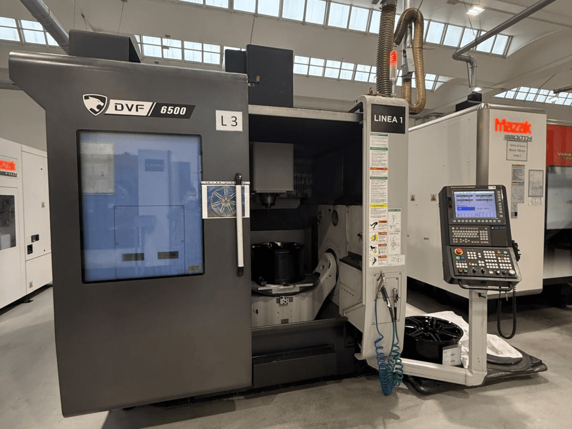 Máquina CNC DVF 6500, vista frontal, mostrando o painel de controlo e o espaço interior com uma peça de fixação.