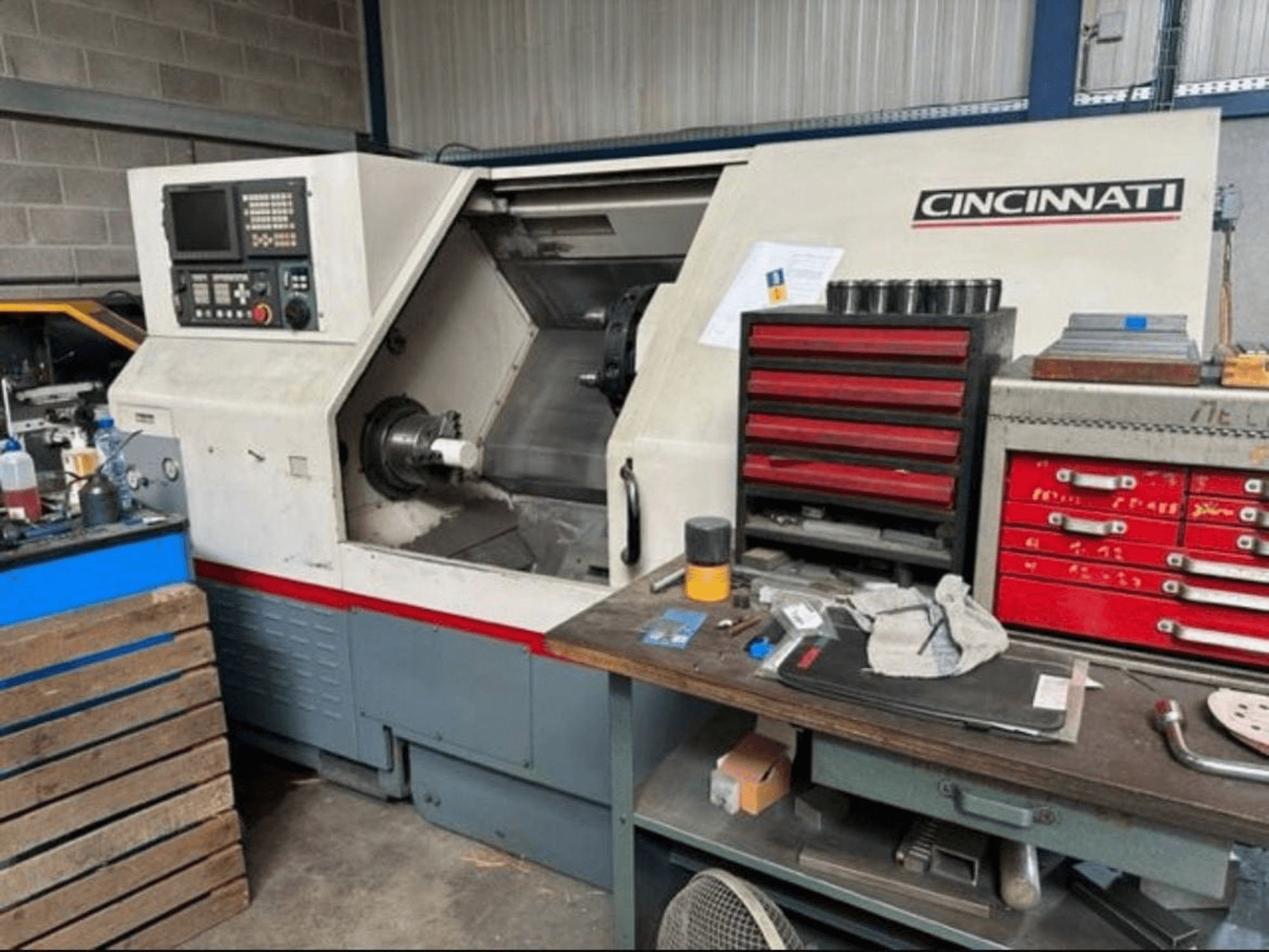 Torno horizontal Cincinnati HAWK 200, vista lateral que mostra o painel de controlo, a área de trabalho e o espaço de armazenamento de ferramentas nas proximidades.