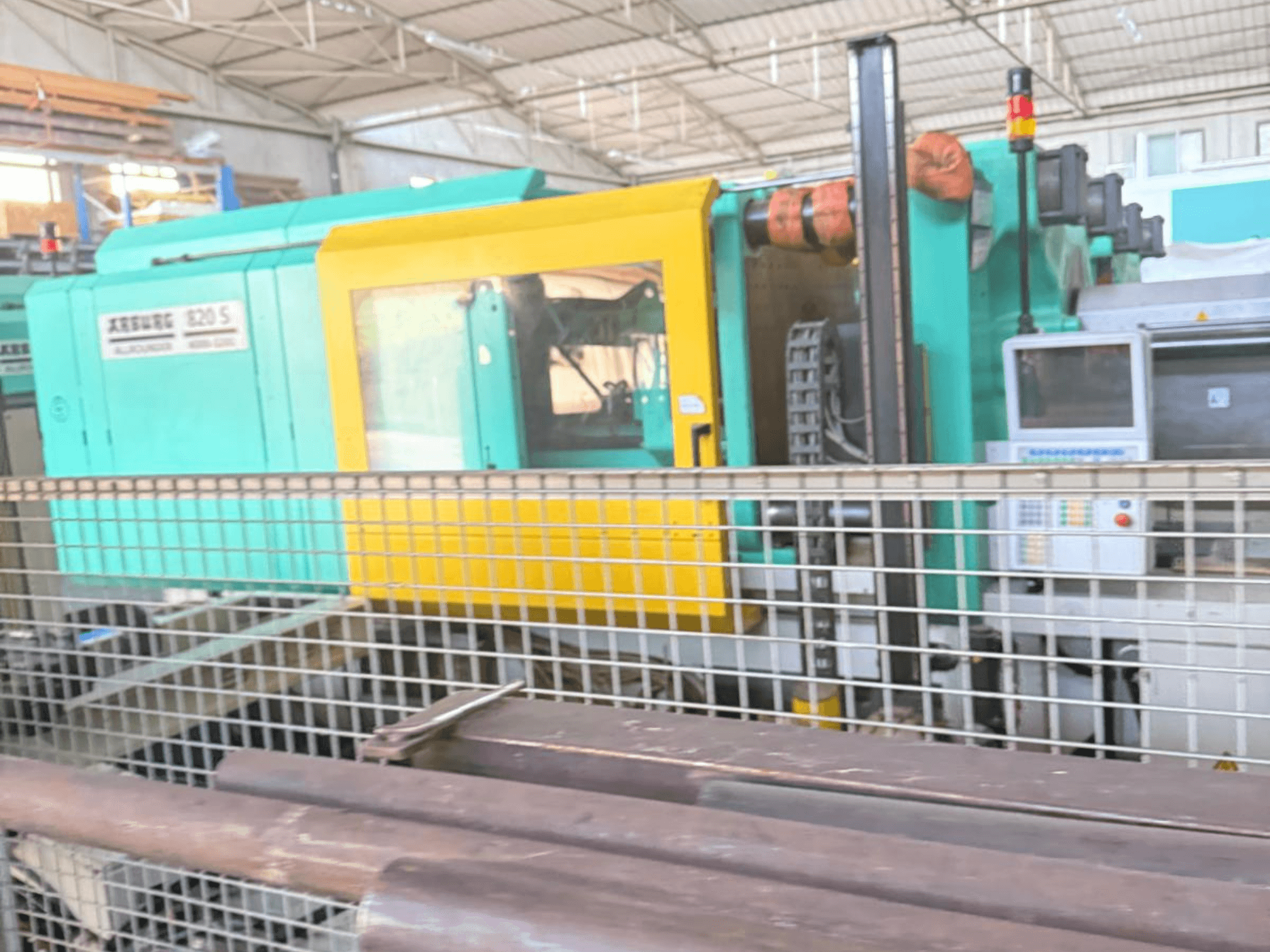 Máquina de moldagem por injeção hidráulica Arburg SELECTA 820 S 4000-3200, vista lateral, mostrando o painel de controlo e o design vibrante em amarelo e azul-petróleo.