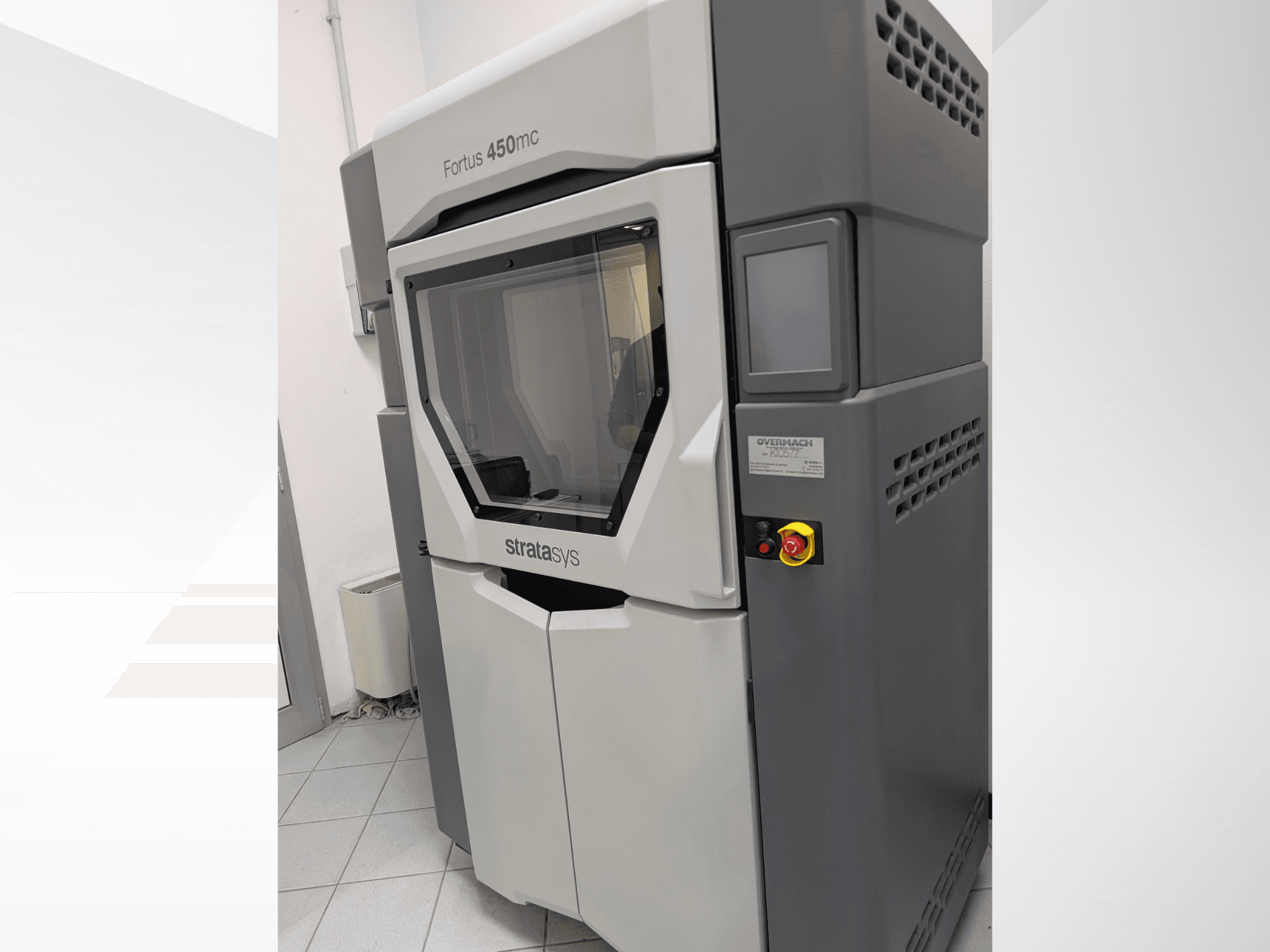 Impressora 3D de plástico Fortus 450mc apresentada em vista lateral, com um painel frontal transparente e botões de controlo laterais.