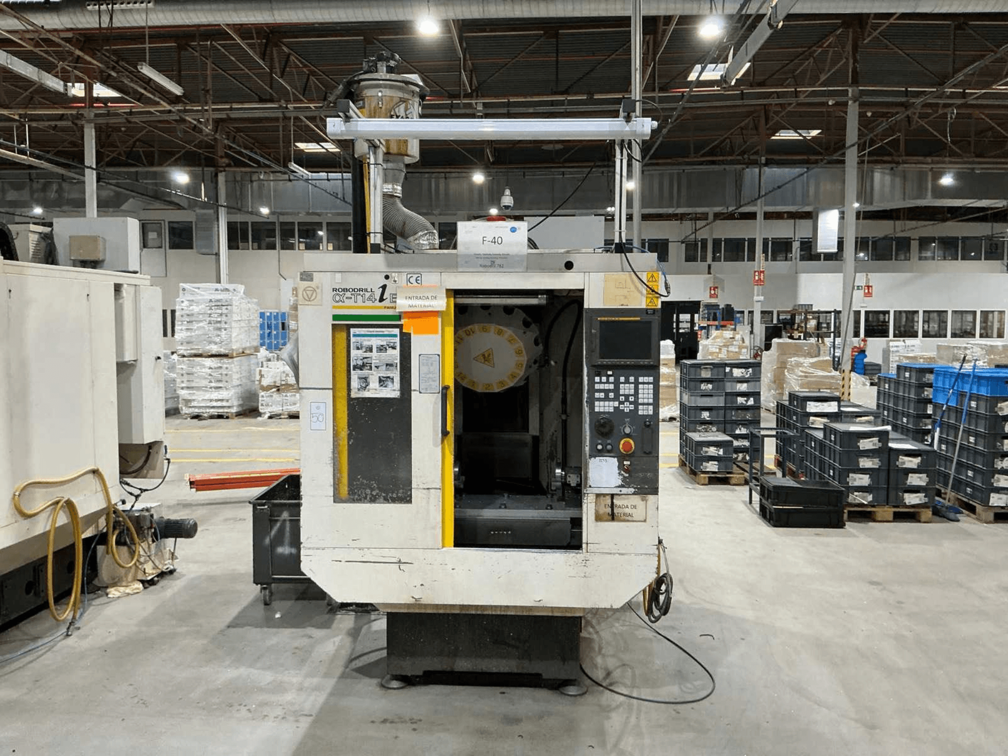 Centro de maquinação vertical FANUC ROBODRILL α-T14iB numa fábrica, vista frontal mostrando o painel de controlo e o suporte de ferramentas.