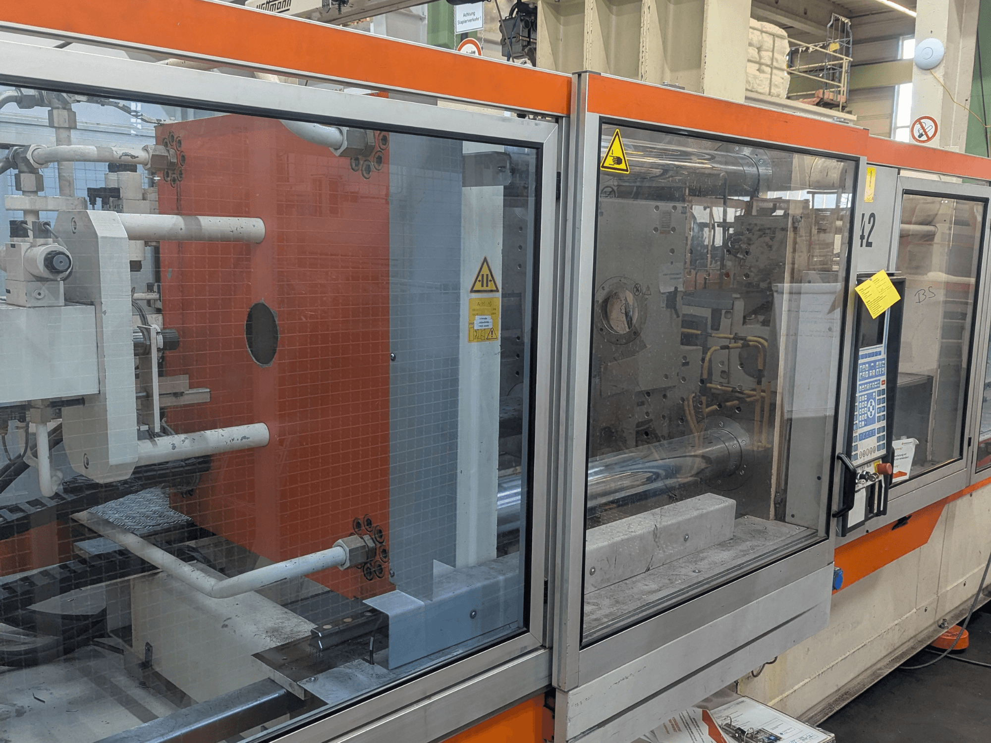 Vista frontal de uma máquina de moldagem por injeção hidráulica DEMAG SYSTEC 80/420-310 com painel de controlo visível e componentes da máquina.