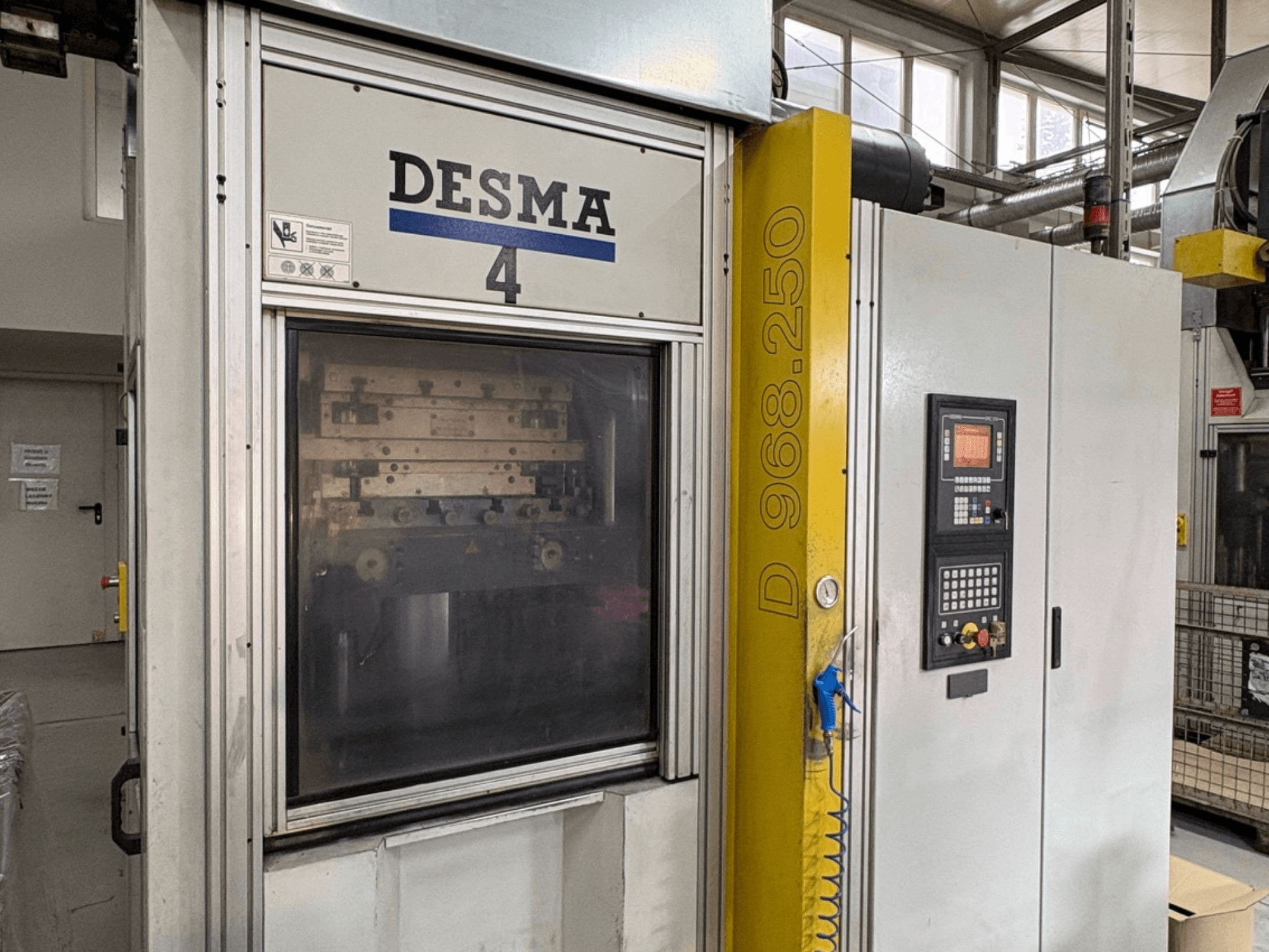 Máquina de moldagem por injeção vertical Kloeckner Desma 968.250, vista frontal mostrando o painel de controlo e os detalhes da máquina.