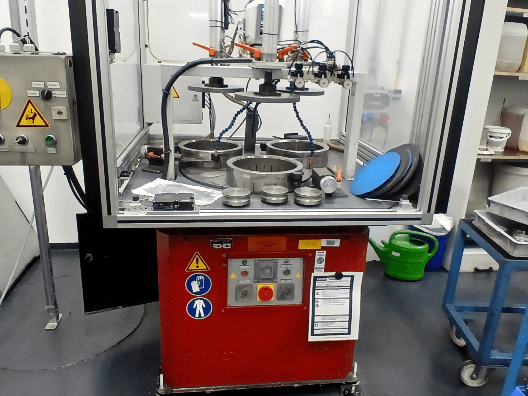 Máquina-ferramenta MYLÄP 700 em vista frontal, mostrando o painel de controlo, componentes circulares e caraterísticas de segurança numa base vermelha.