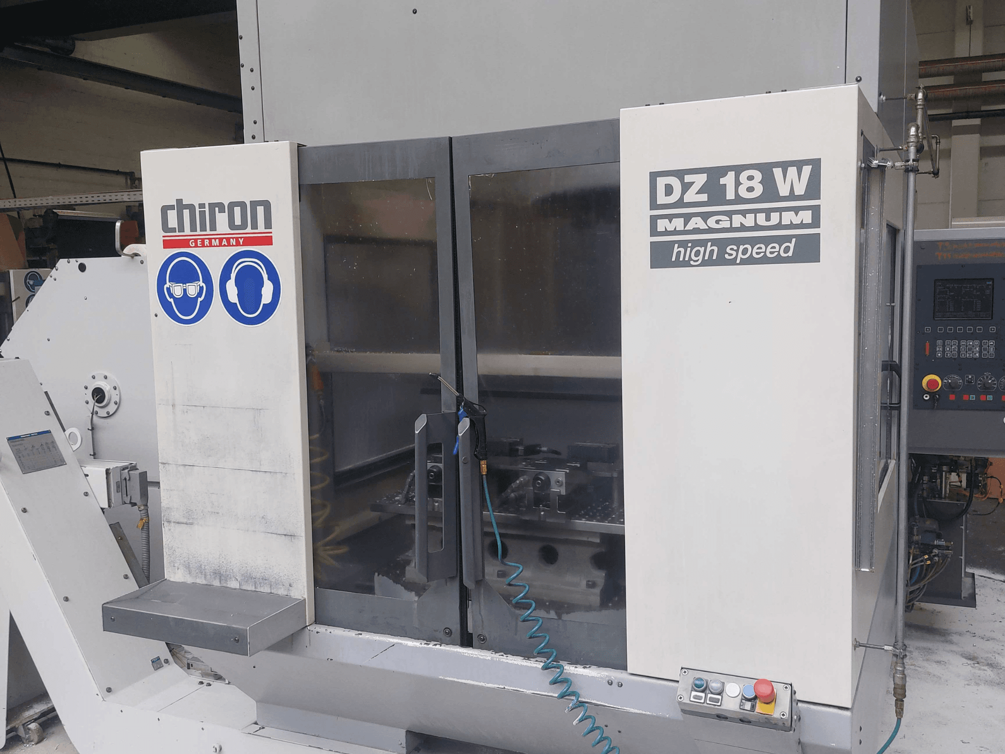 Centro de maquinagem vertical CHIRON DZ 18 W MAGNUM, vista frontal mostrando o painel de controlo e os sinais de segurança.