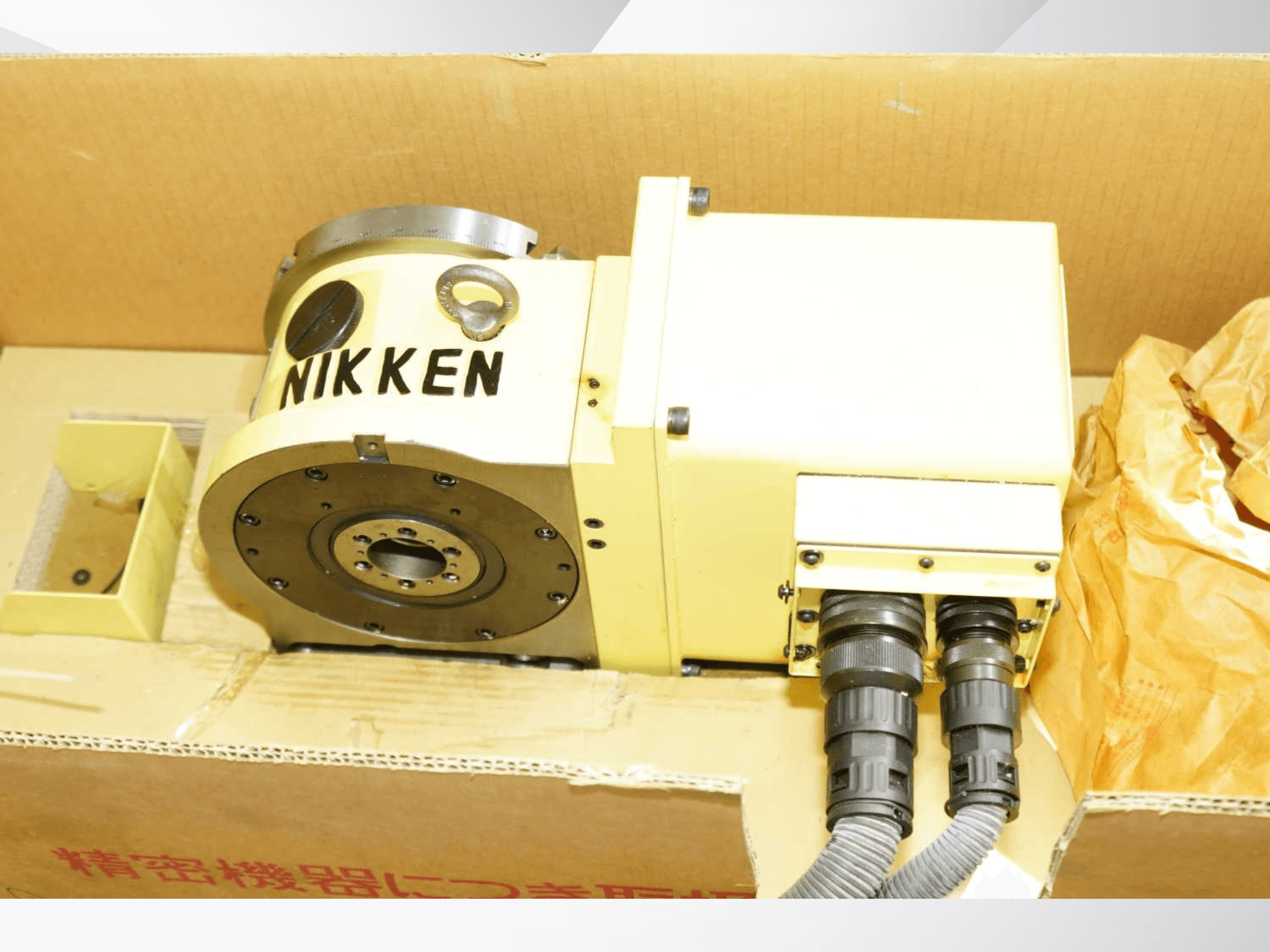 Mesa rotativa NIKKEN em amarelo com conectores, vista frontal, apresentando componentes de maquinagem para operações precisas.