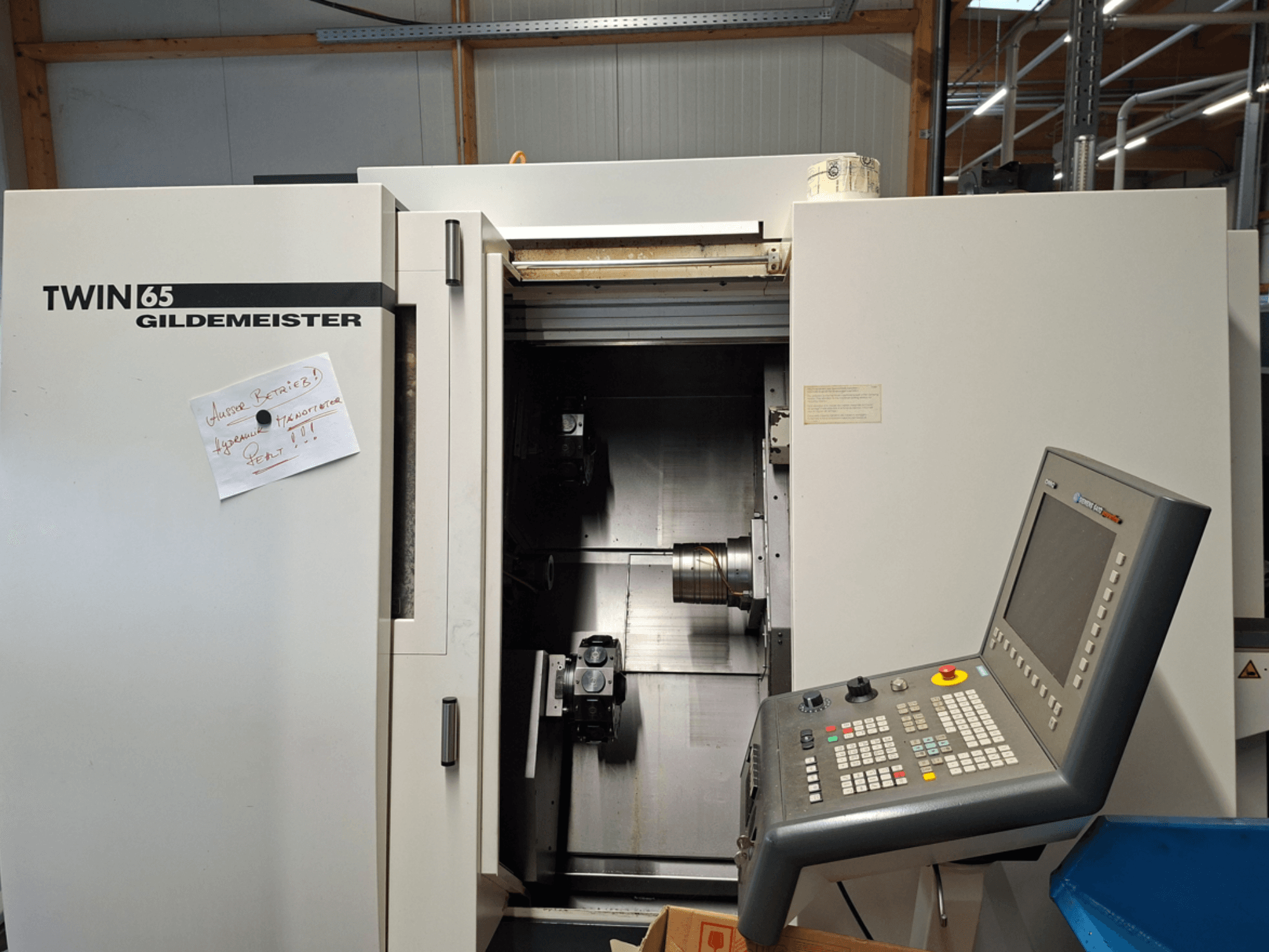 Torno CNC Gildemeister TWIN 65, vista frontal mostrando painel de controlo e câmara parcialmente aberta com maquinaria visível.