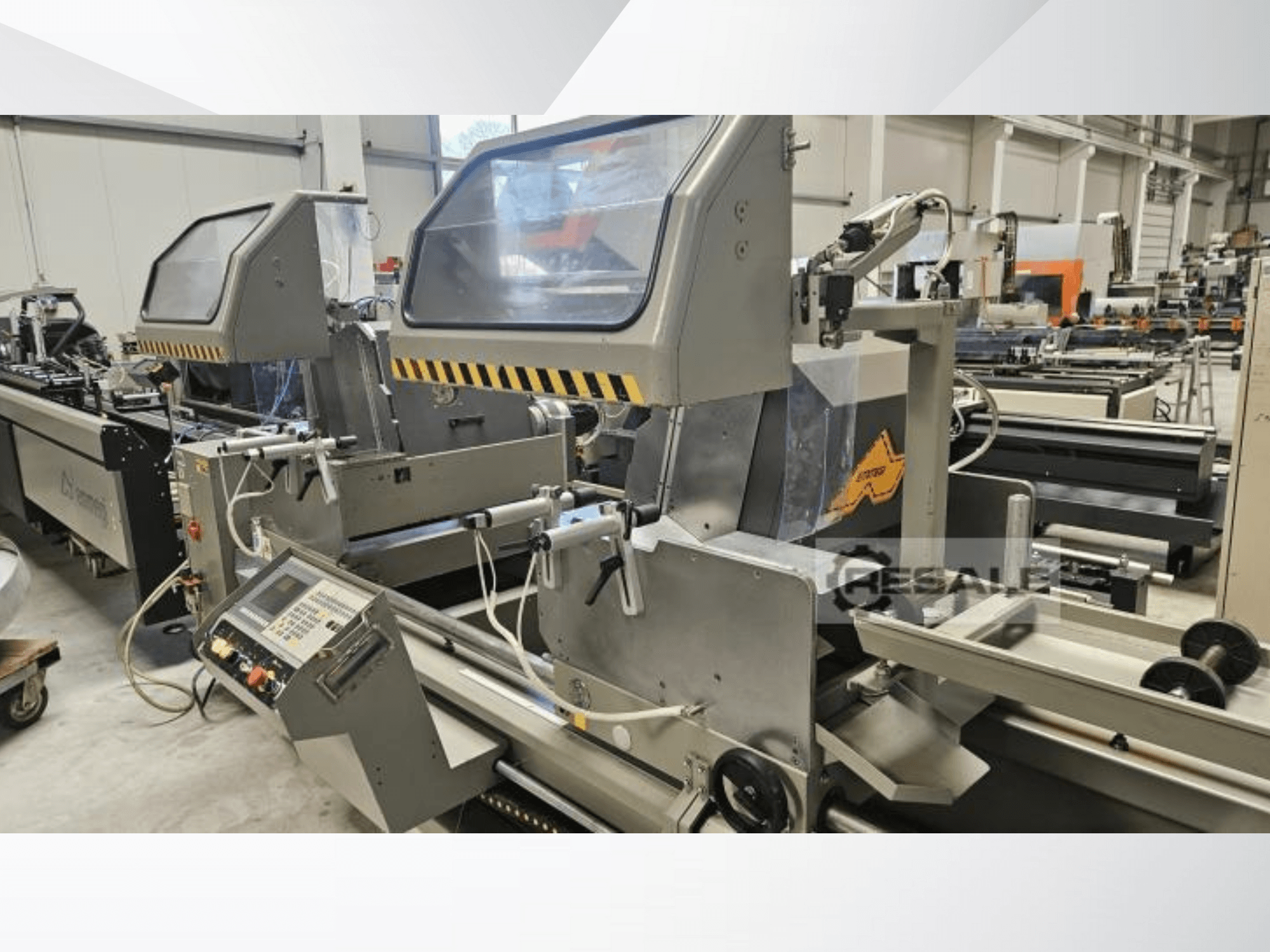 Máquinas de serra dupla em ambiente fabril; vista frontal mostrando o painel de controlo, as tampas de vidro e os componentes de corte.