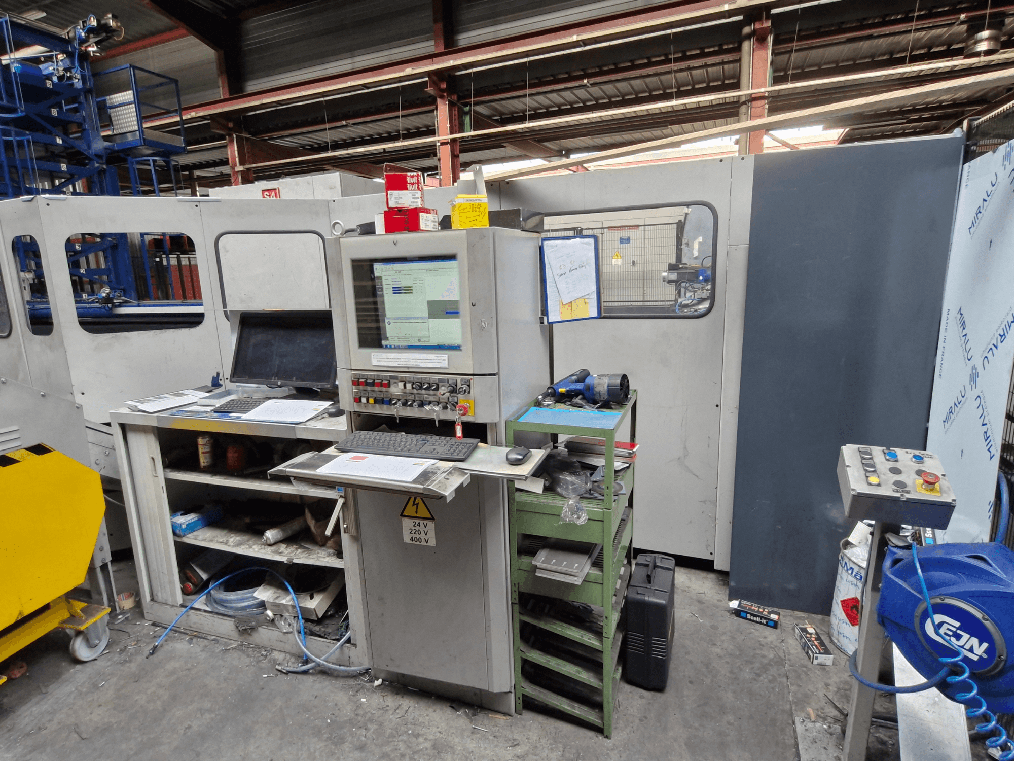Puncionadora CNC Salvagnini S4-40 numa oficina, com um painel de controlo com monitores e ferramentas, vista frontal.