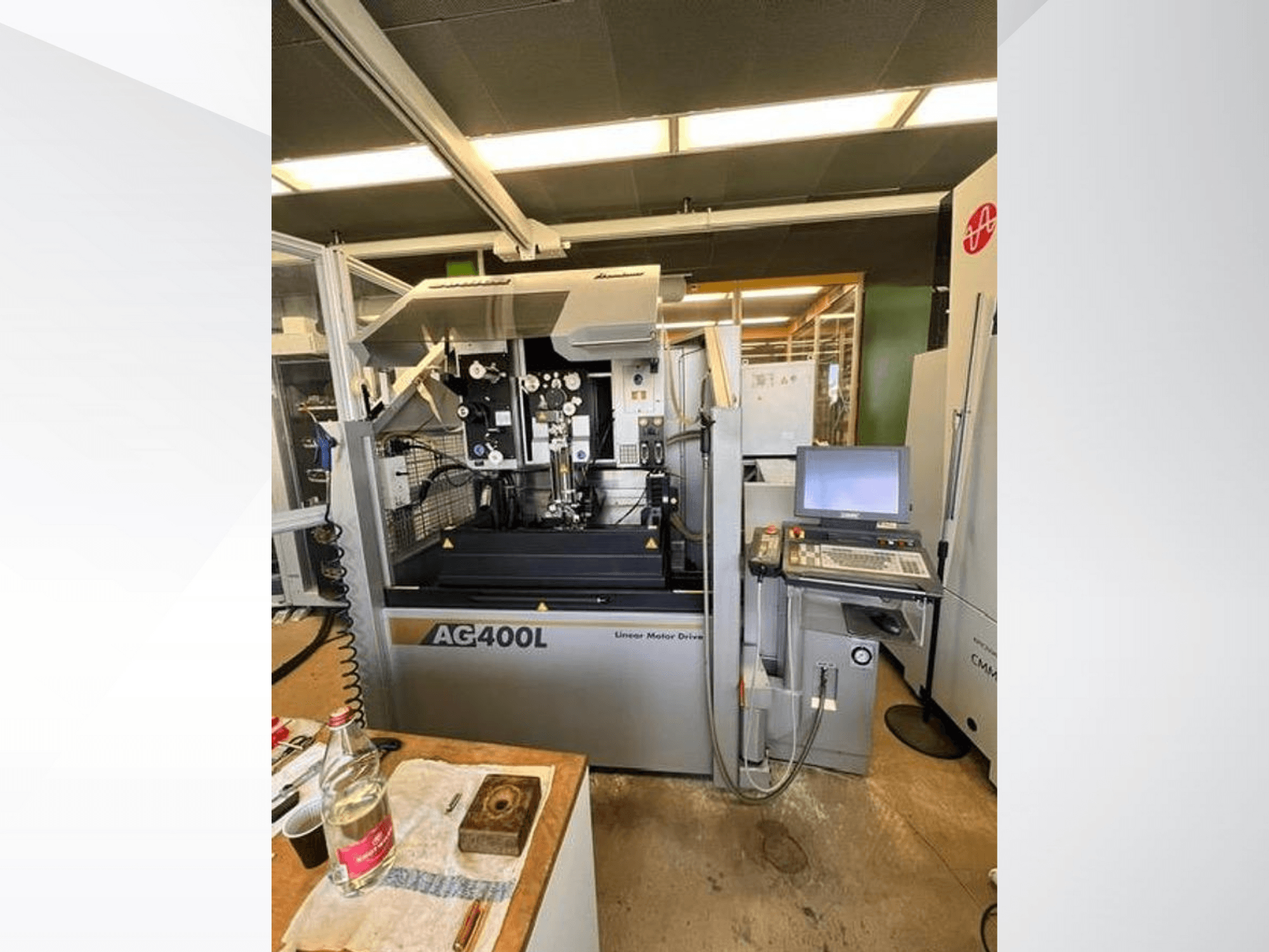 Máquina de acionamento por motor linear AG400L, vista frontal, com painel de controlo e área de trabalho com caraterísticas de segurança visíveis.