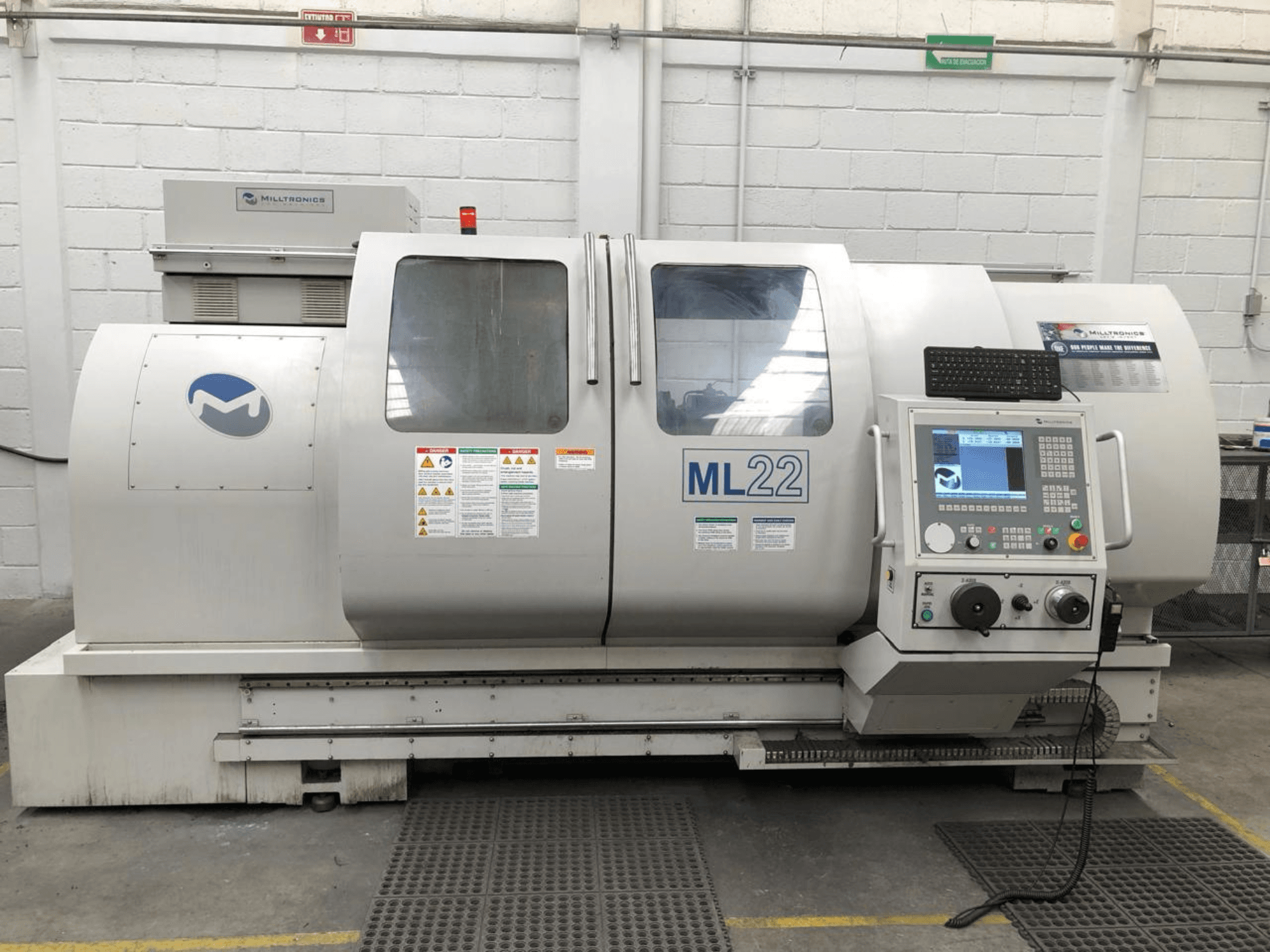 Centro de maquinação vertical MILLTRONICS RH 20, vista frontal mostrando o painel de controlo, o logótipo da marca e as etiquetas de segurança na máquina.