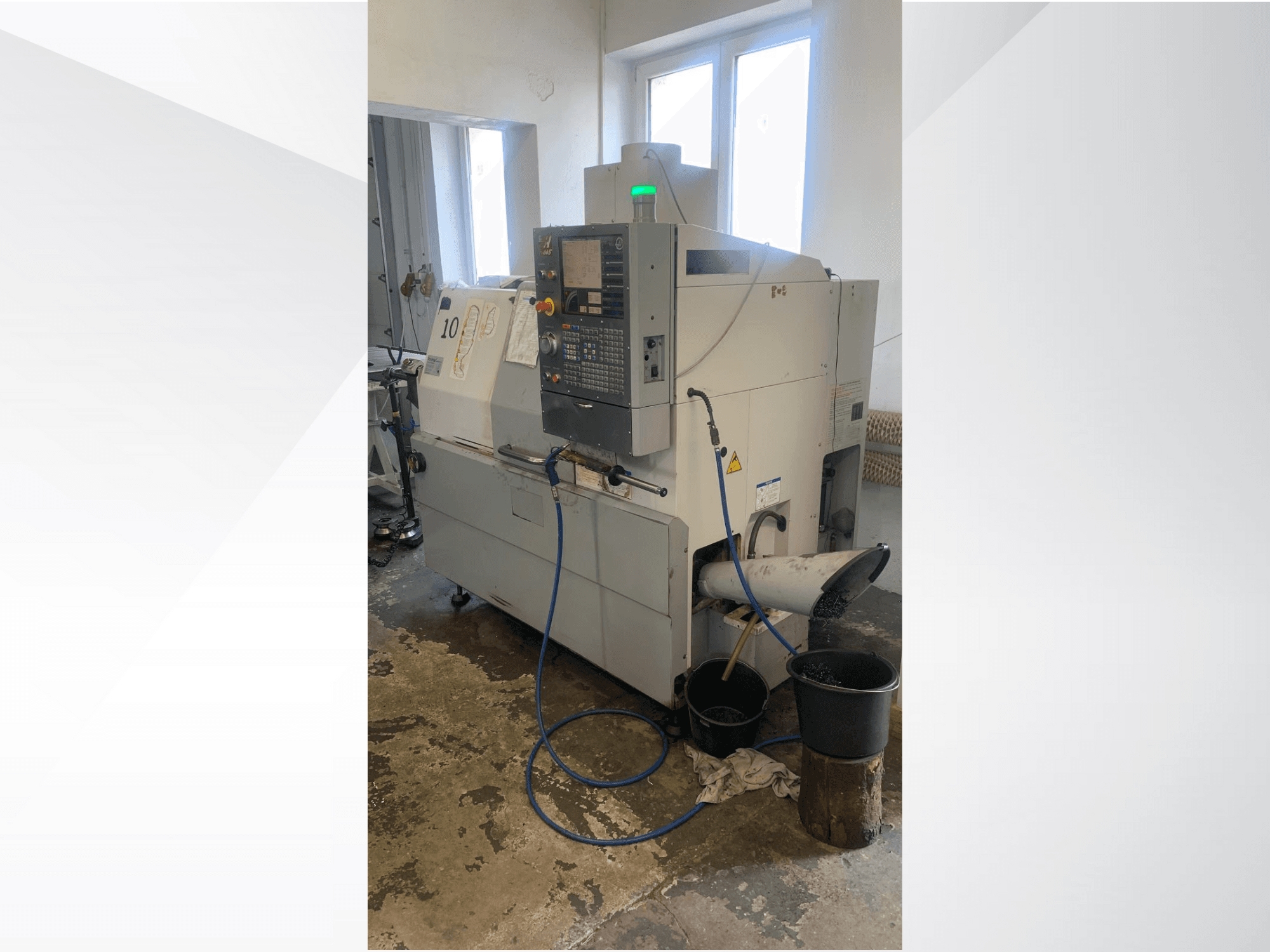 Modelo de máquina CNC Haas com painel de controlo, vista lateral, com linha de refrigeração, calha de resíduos e recipientes de armazenamento por baixo.