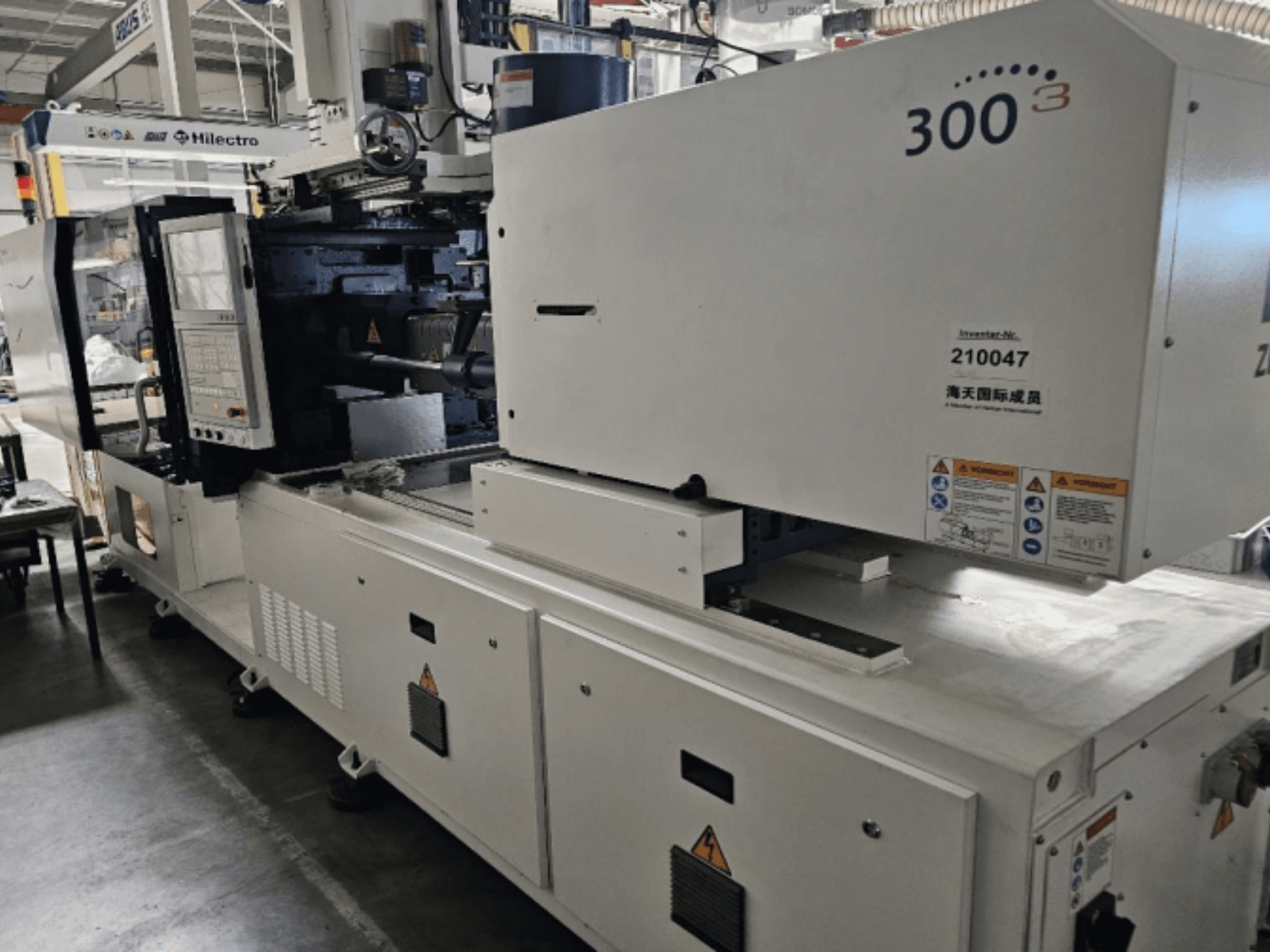 Máquina de moldagem por injeção, marca Zhenjing, modelo 300, vista frontal com painel de controlo e etiquetas de aviso de segurança visíveis.