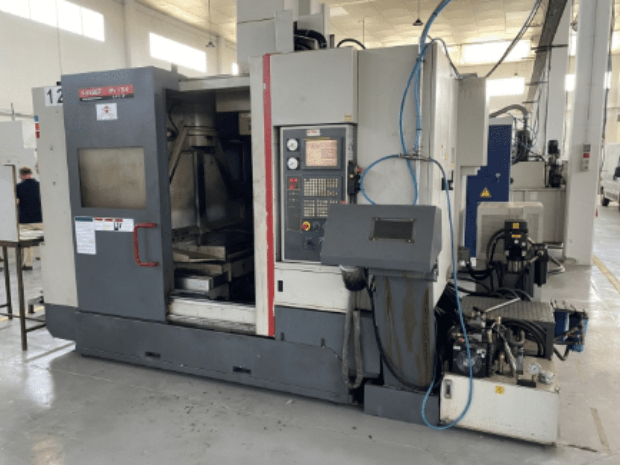 Centro de maquinação vertical Quaser MV154APC-912, vista frontal mostrando o painel de controlo, a porta aberta e os componentes da máquina.