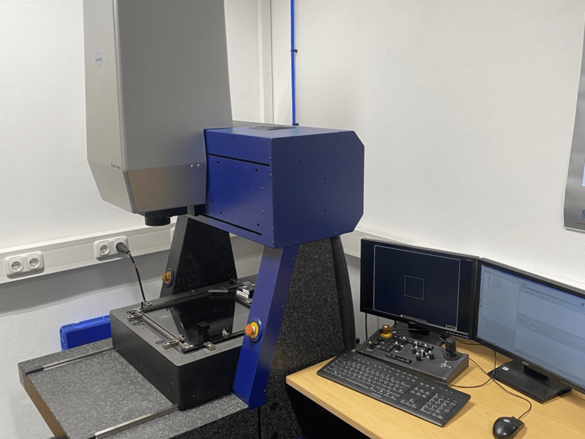 CMM Werth Scope-Check 400 num laboratório, mostrando a cabeça de medição e o painel de controlo com ecrãs e teclado.