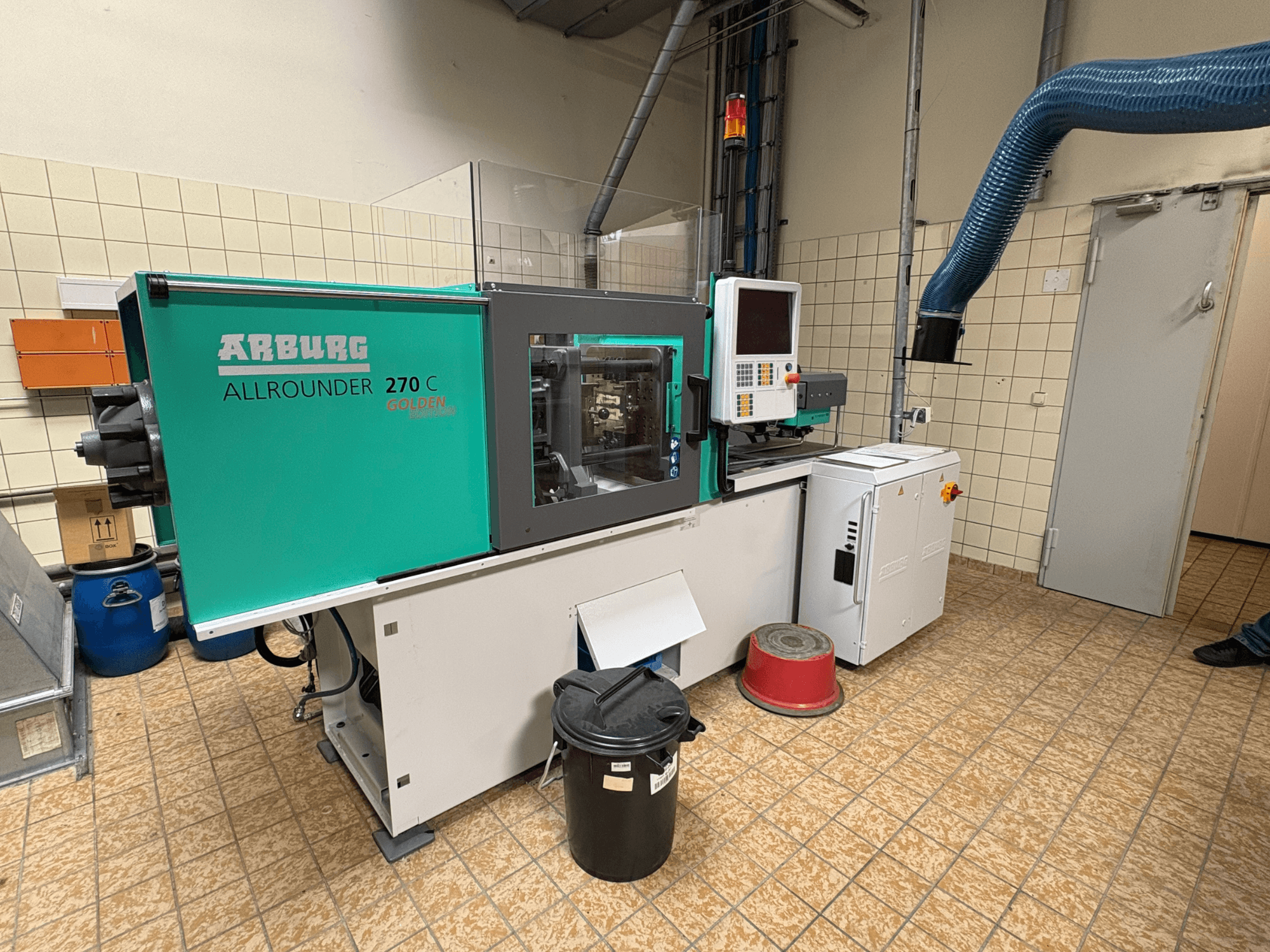 Máquina de moldagem por injeção hidráulica Arburg ALLROUNDER 270 C vista de lado, com os comandos e o equipamento ligado.