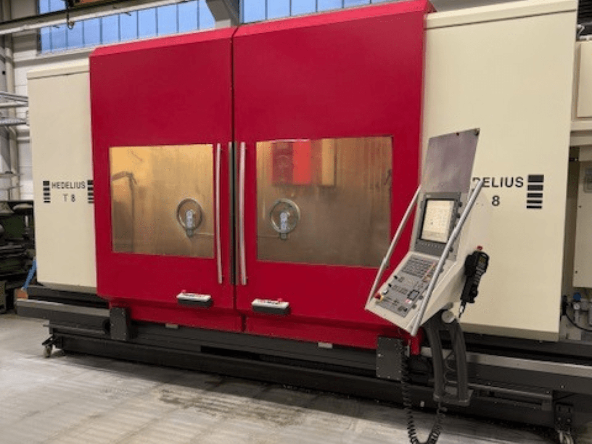 Máquina CNC HEDELIUS T8 em vista frontal, com portas vermelhas, painel de controlo e visibilidade dos componentes internos.