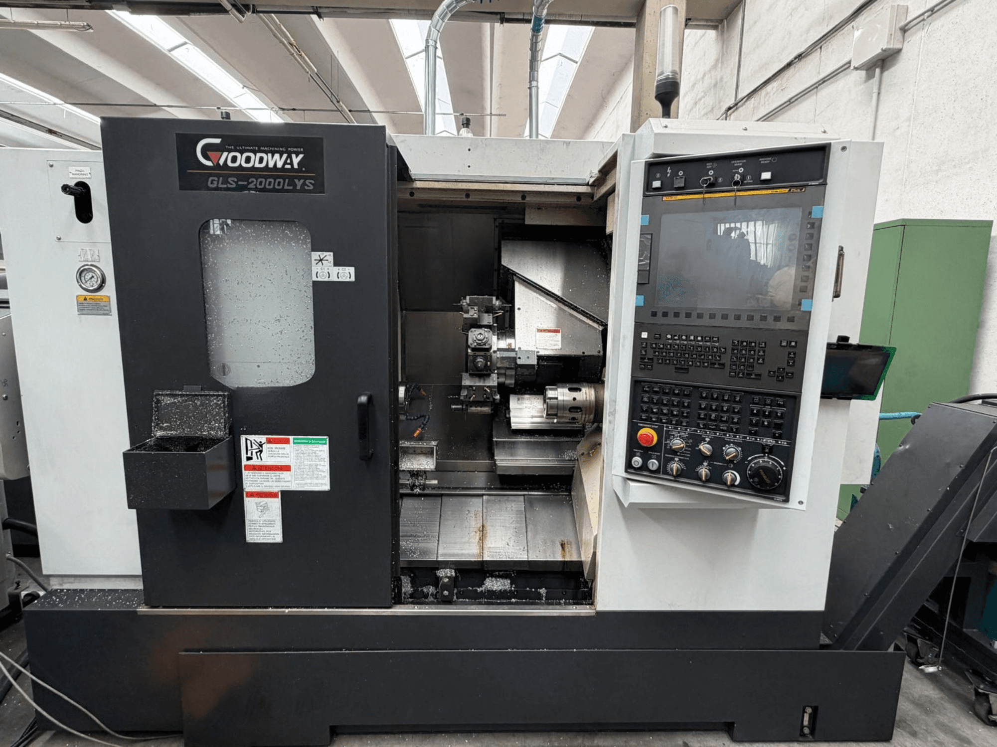 Torno horizontal Goodway GLS-2000LYS visto de frente, com o painel de controlo e as limalhas de metal visíveis.