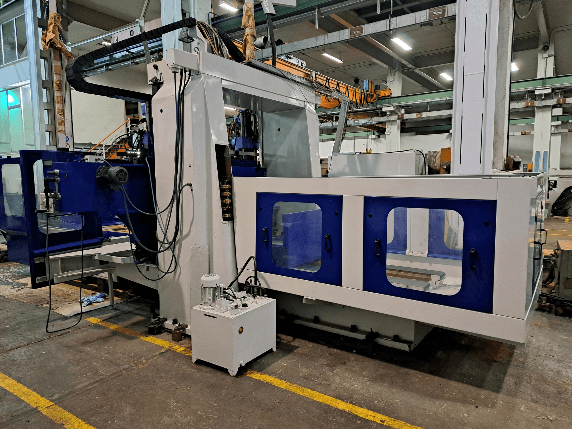 Fresadora de bancada DYE RHE-3000 numa oficina, vista frontal que mostra a sua grande estrutura azul e branca e o painel de controlo.