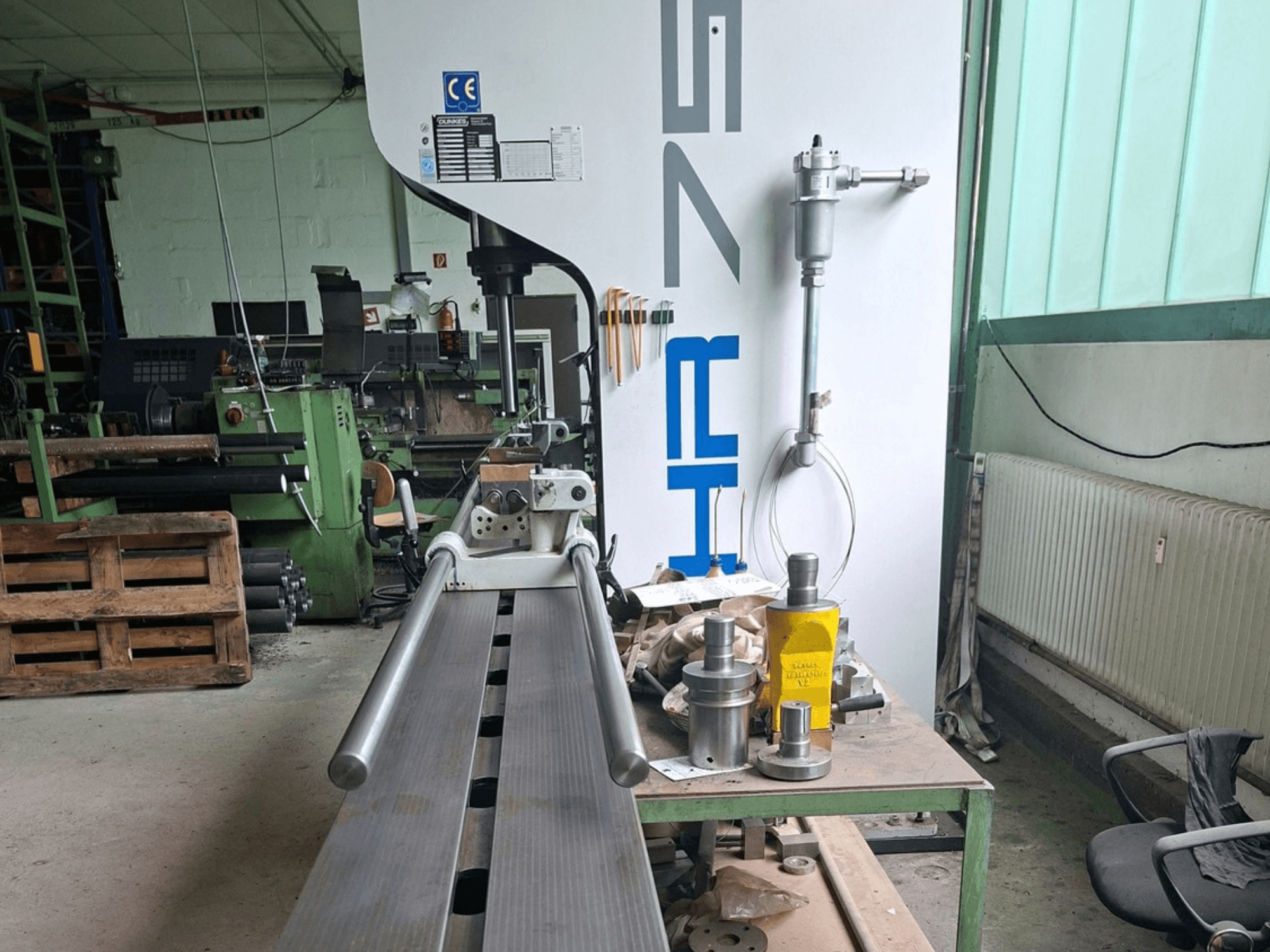 Prensa metálica Dunkes HR75 na oficina, vista lateral que mostra o perfil e as ferramentas à volta na mesa.
