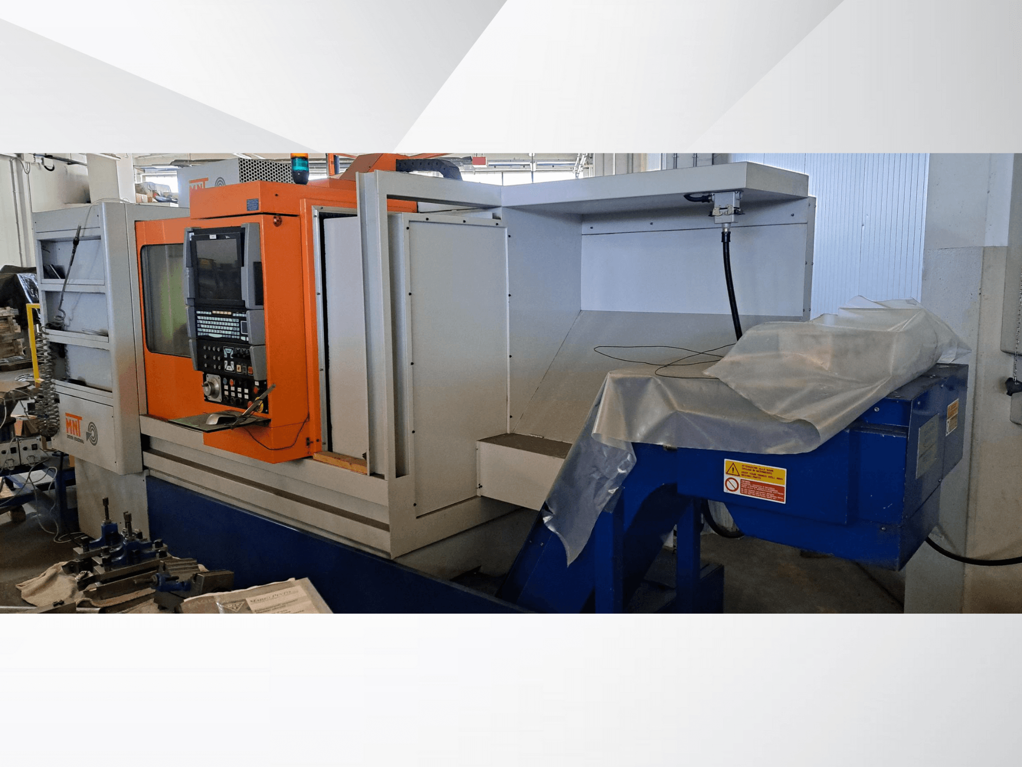 Máquina CNC MNT, vista frontal, com painel de controlo laranja, grande área de maquinação e unidade de eliminação de aparas azul.