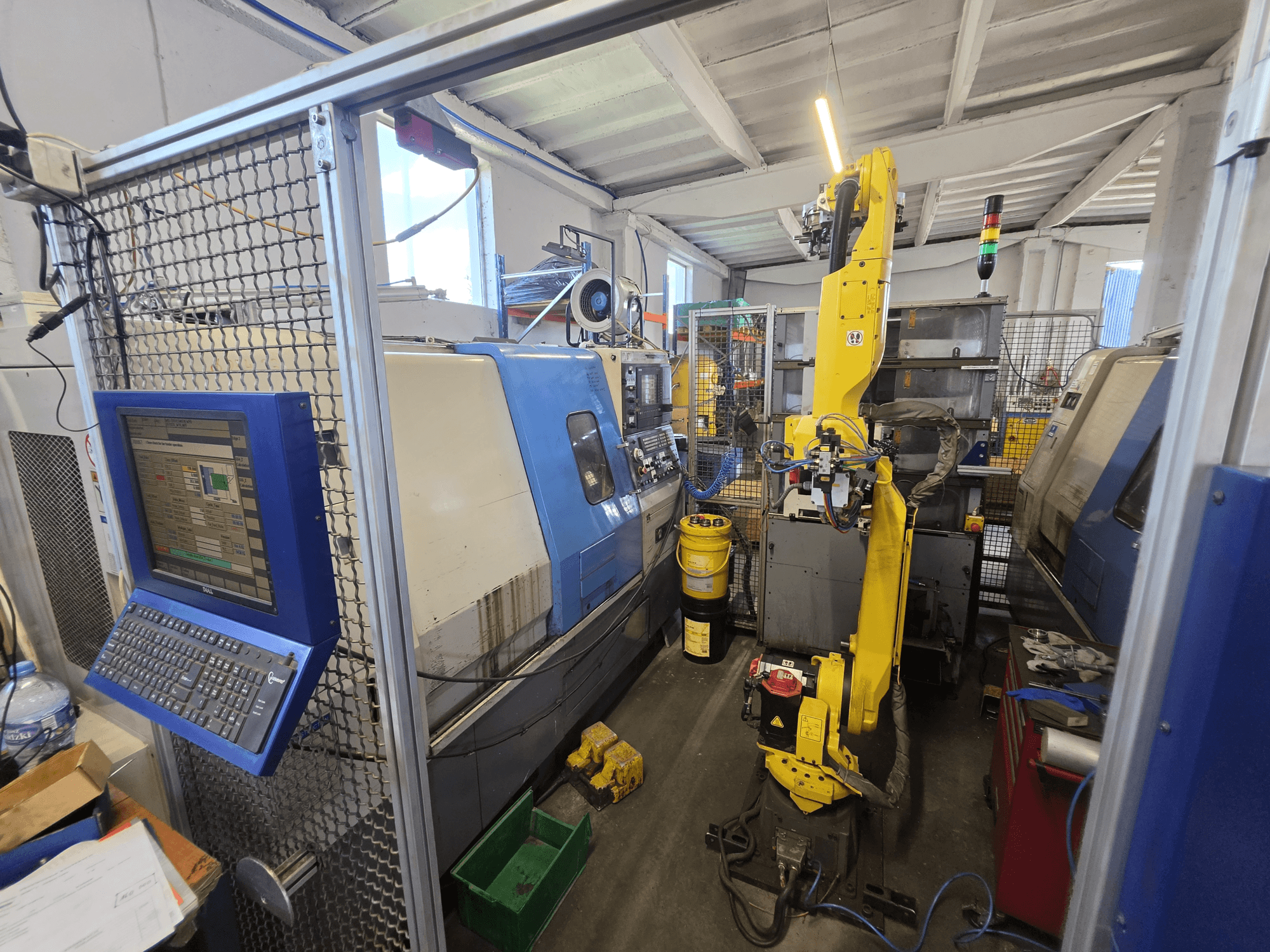 Torno horizontal Hyundai HIT-200C com robô FANUC M-20iA, vista frontal que mostra a interface de controlo e a configuração da máquina.