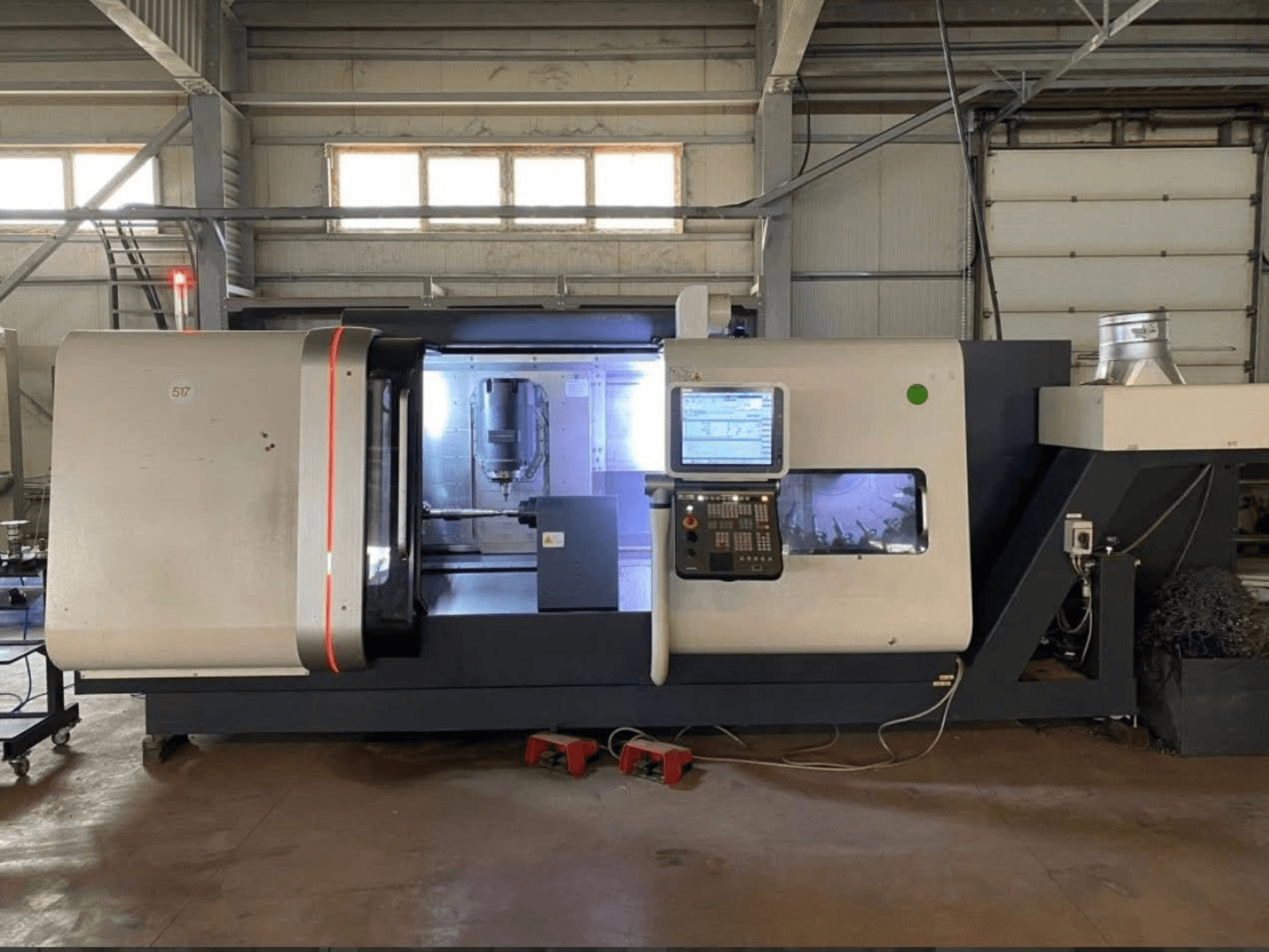 Centro de torneamento-fresagem DMG MORI Beta 1250 TC, vista frontal com painel de controlo, área de trabalho iluminada e ferramentas de corte visíveis.