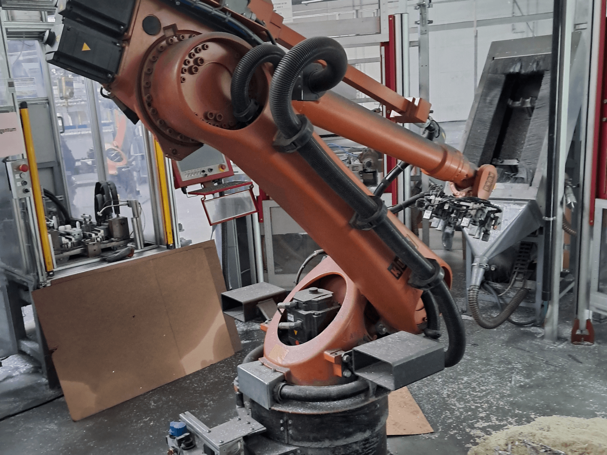 Braço robótico KUKA KR 30 L 16-2 numa oficina, vista frontal. Apresenta articulações e um fundo que representa um espaço de trabalho industrial.