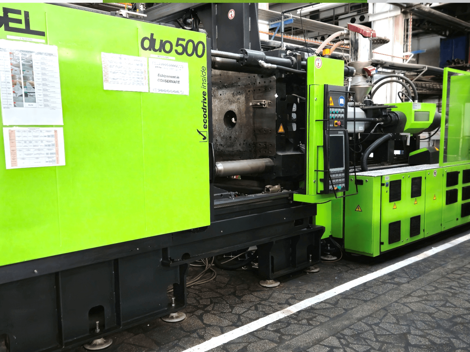 Máquina industrial verde Ergotron duo 500, vista frontal; com painel de controlo, detalhes técnicos e etiquetas de segurança do equipamento.
