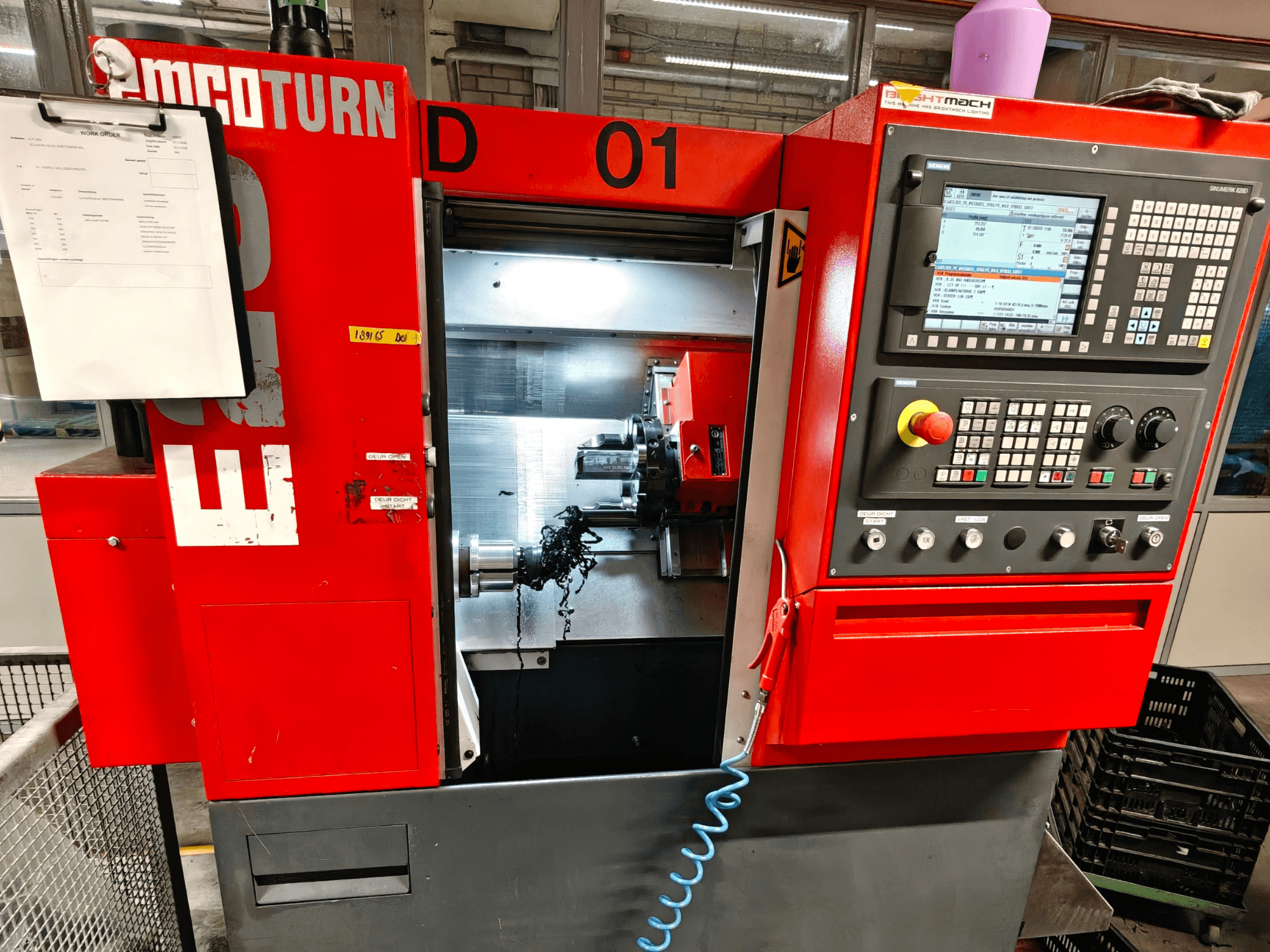 Vista frontal do torneiro horizontal EMCO TURN E25, com controlos operacionais, suporte de ferramentas e área de trabalho com aparas.