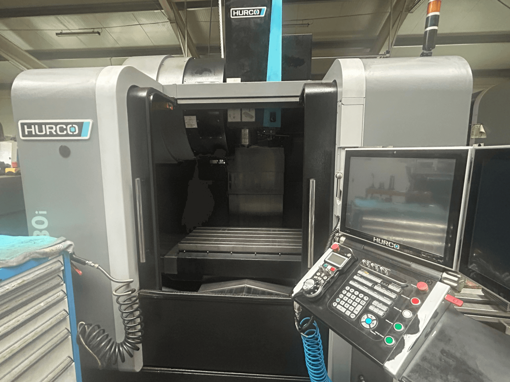 Vista frontal da máquina CNC Hurco VM30i, com painel de controlo com botões, visor e área de armazenamento de ferramentas.