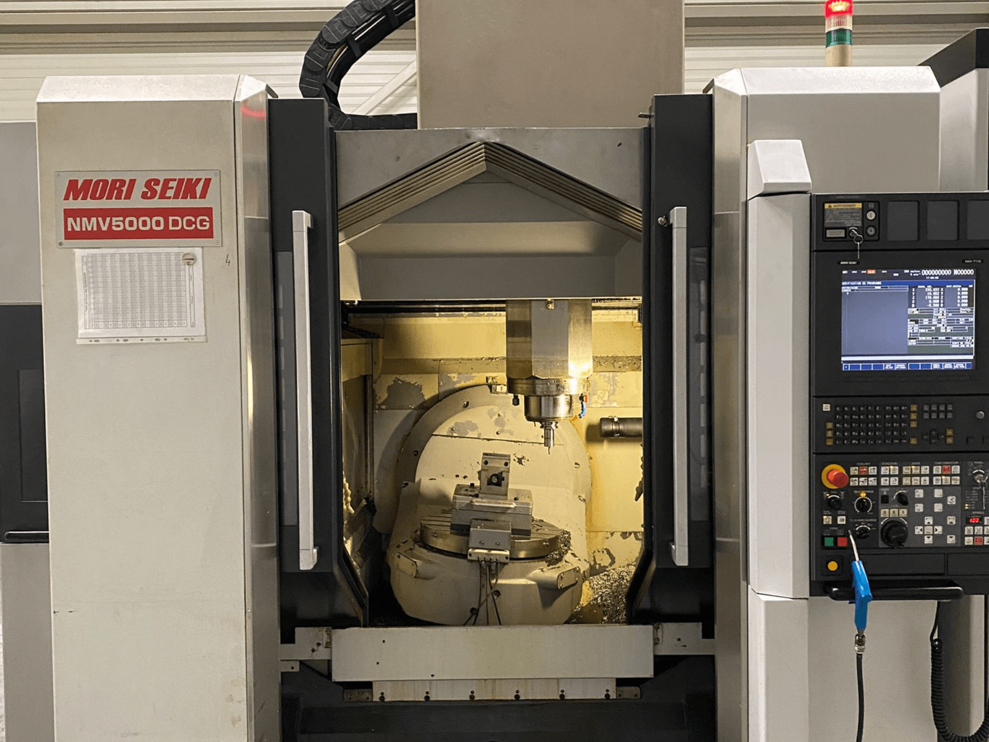 Centro de maquinação universal MORI SEIKI NMV 5000DCG, vista frontal mostrando o painel de controlo e a área de maquinação interior.